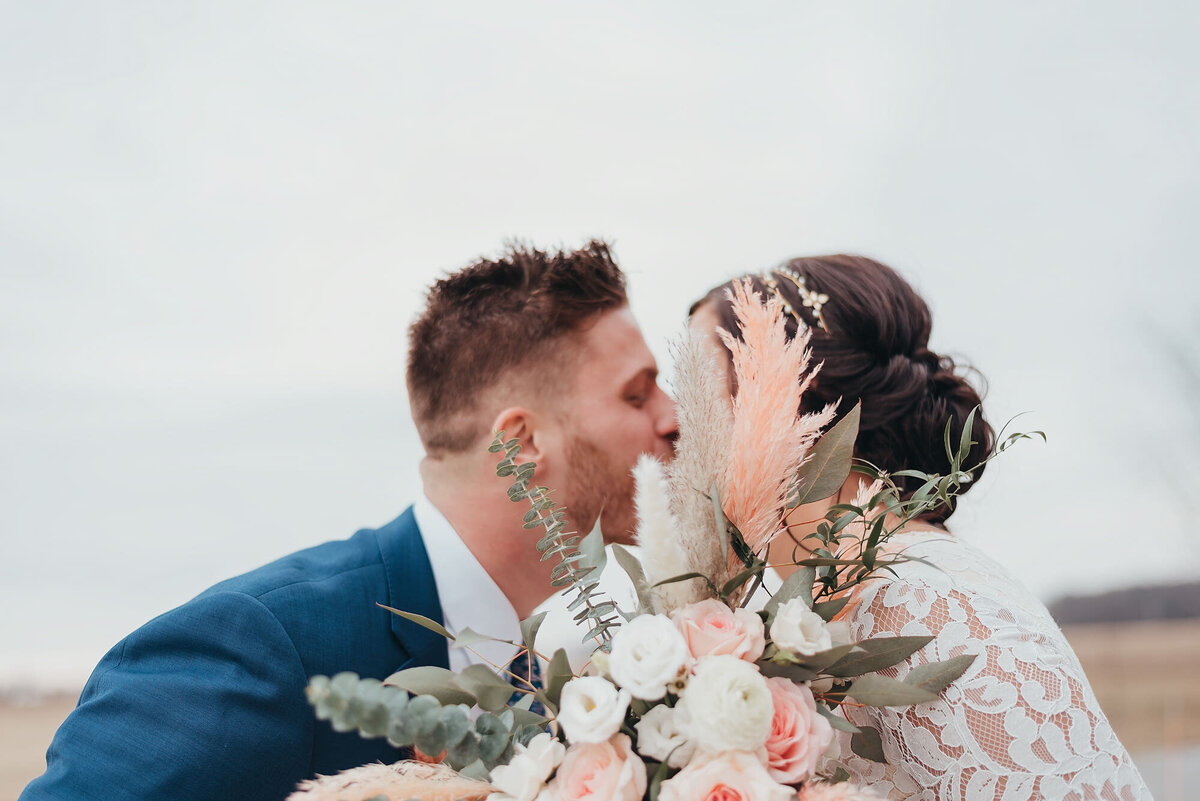 couple kissing behind a bouquet