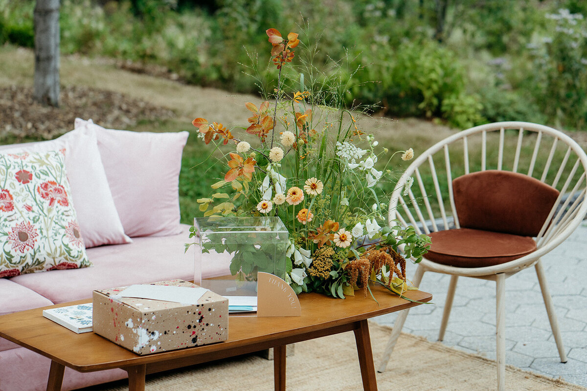 An airy arrangement of white and orange flowers on an outdoor lounge table at a Montreal wedding. 