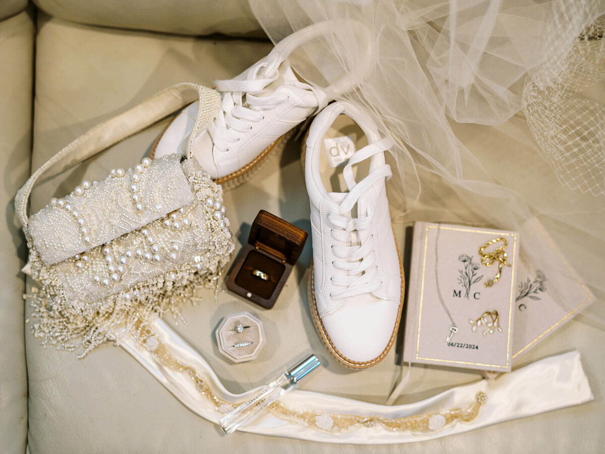 A wedding flat lay featuring shoes, purses, rings  and other items.
