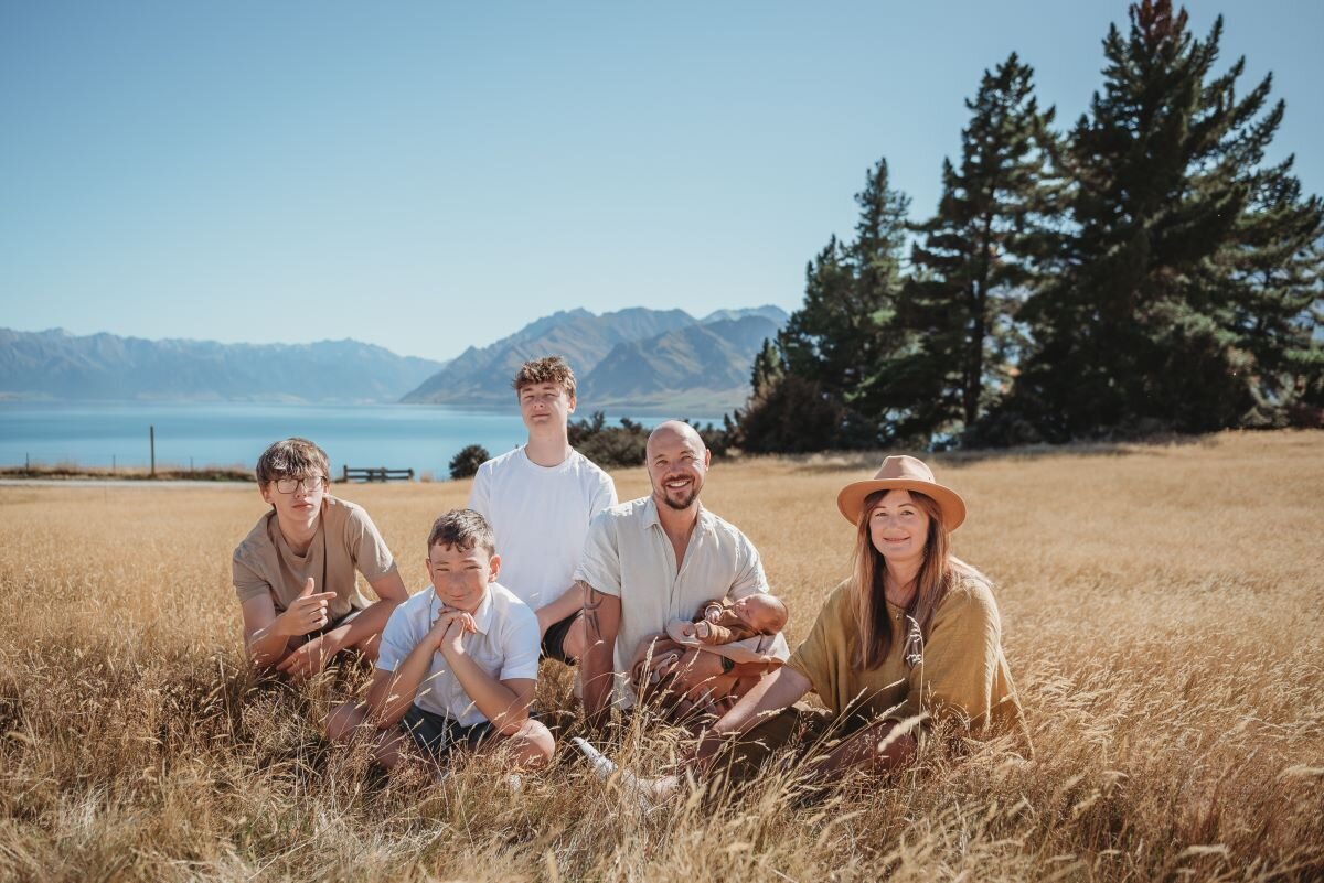 a family of 6 posing in the grass in wanaka for their family photography session