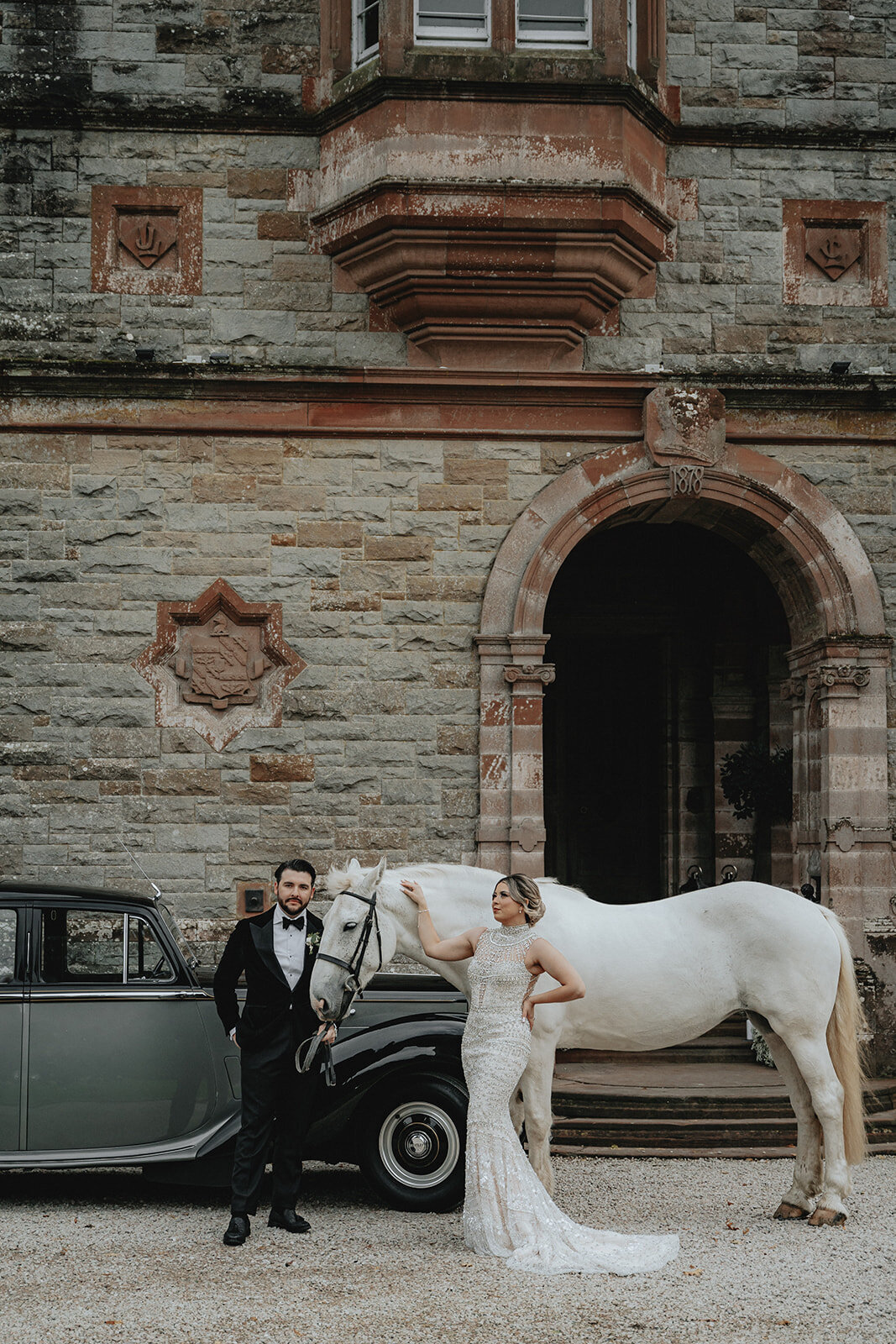 Bride and groom posing with horse and car in front of Ireland castle