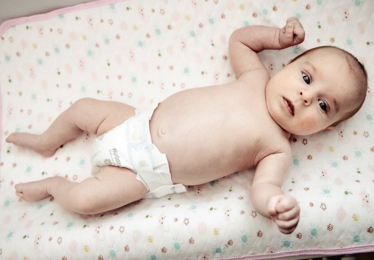 A newborn baby girl laying on her changing table in a diaper