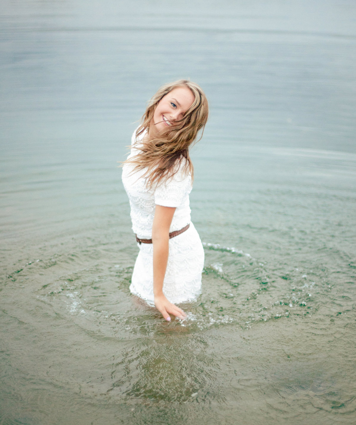 playful senior girl in minnesota lakes dancing in water laughing