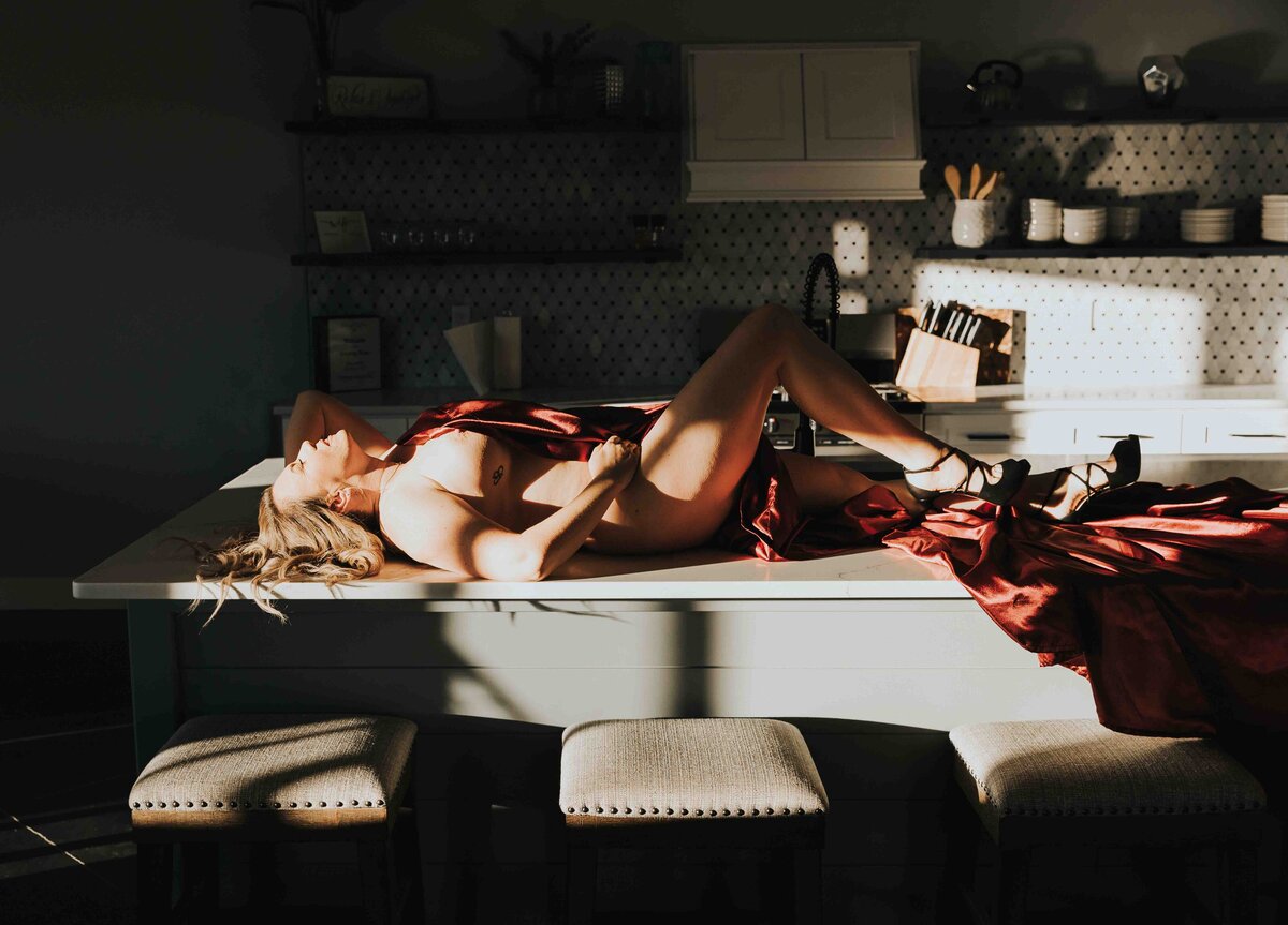 Woman laying on the kitchen counter wearing only a sheet