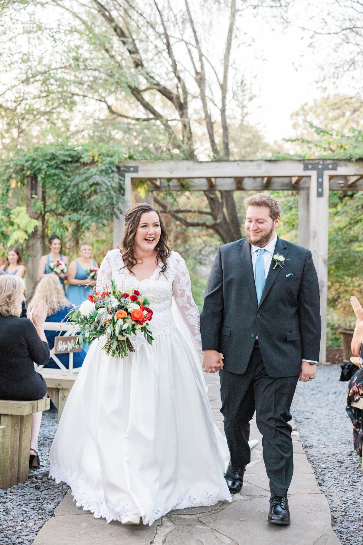 A newlywed couple holding hands and walking back up the aisle