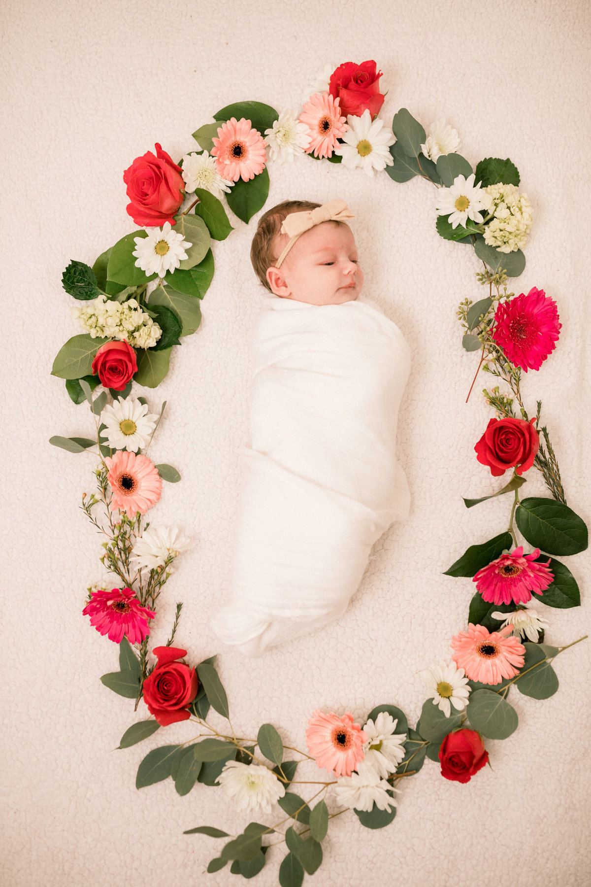Baby lays in the middle of a ring of flowers