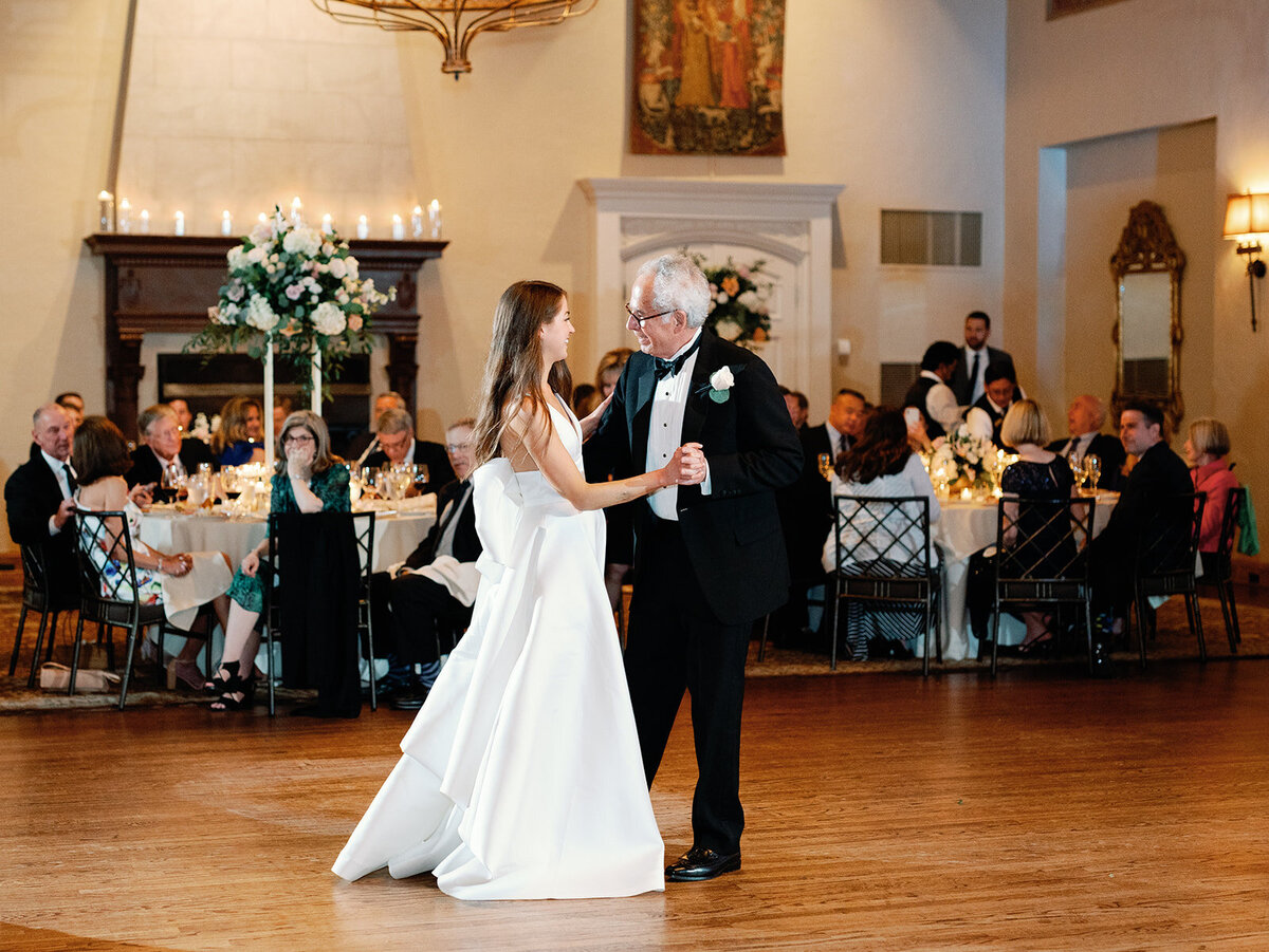 Father and daughter dance in front of wedding guests