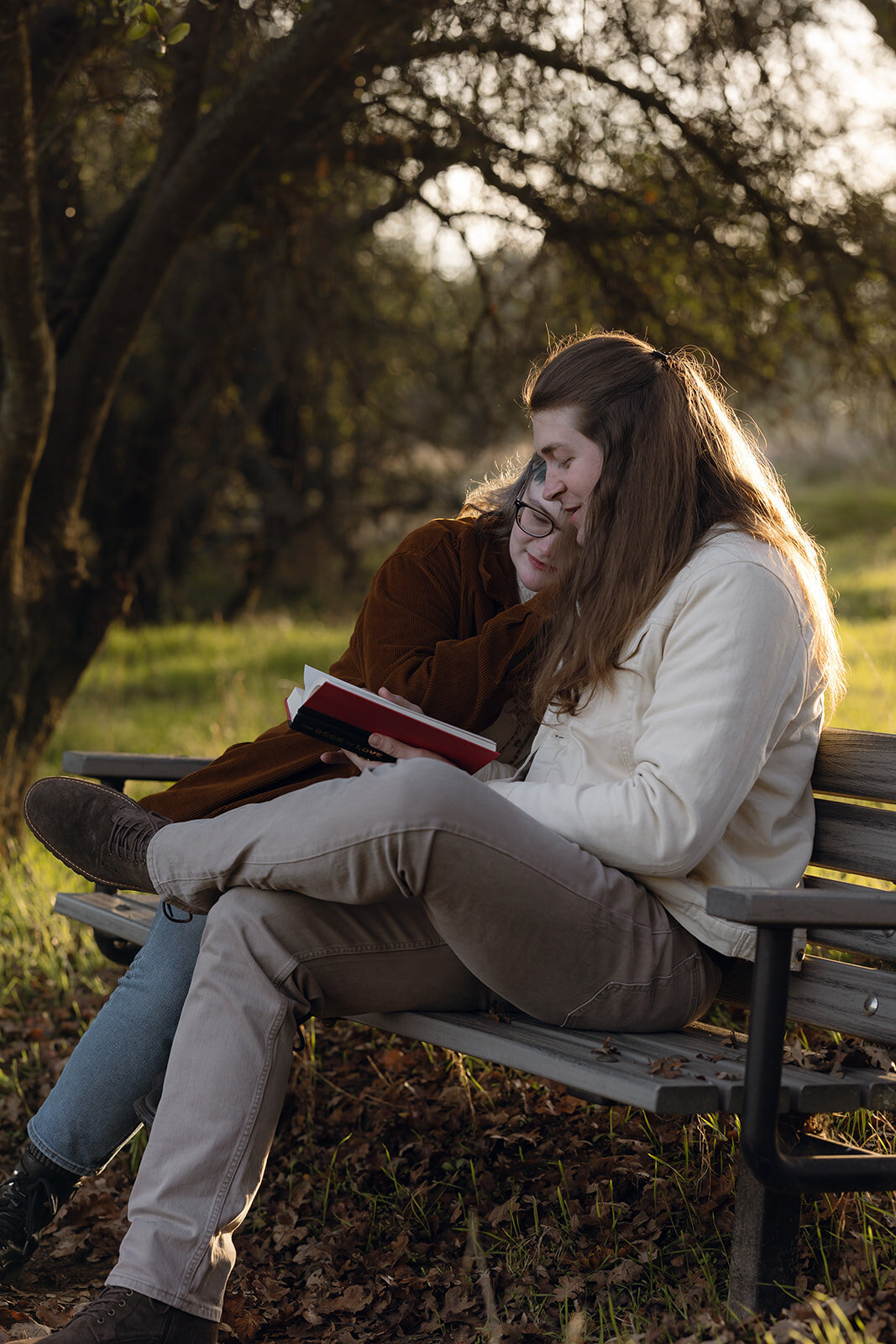 Intimate documentary wedding photography of a couple cuddling on a bench, reading together in golden-hour light in California.