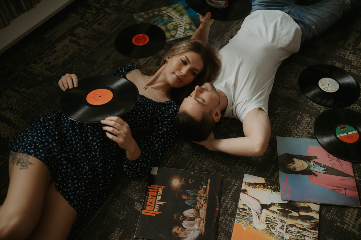 Photographer of couple laying on floor at record store