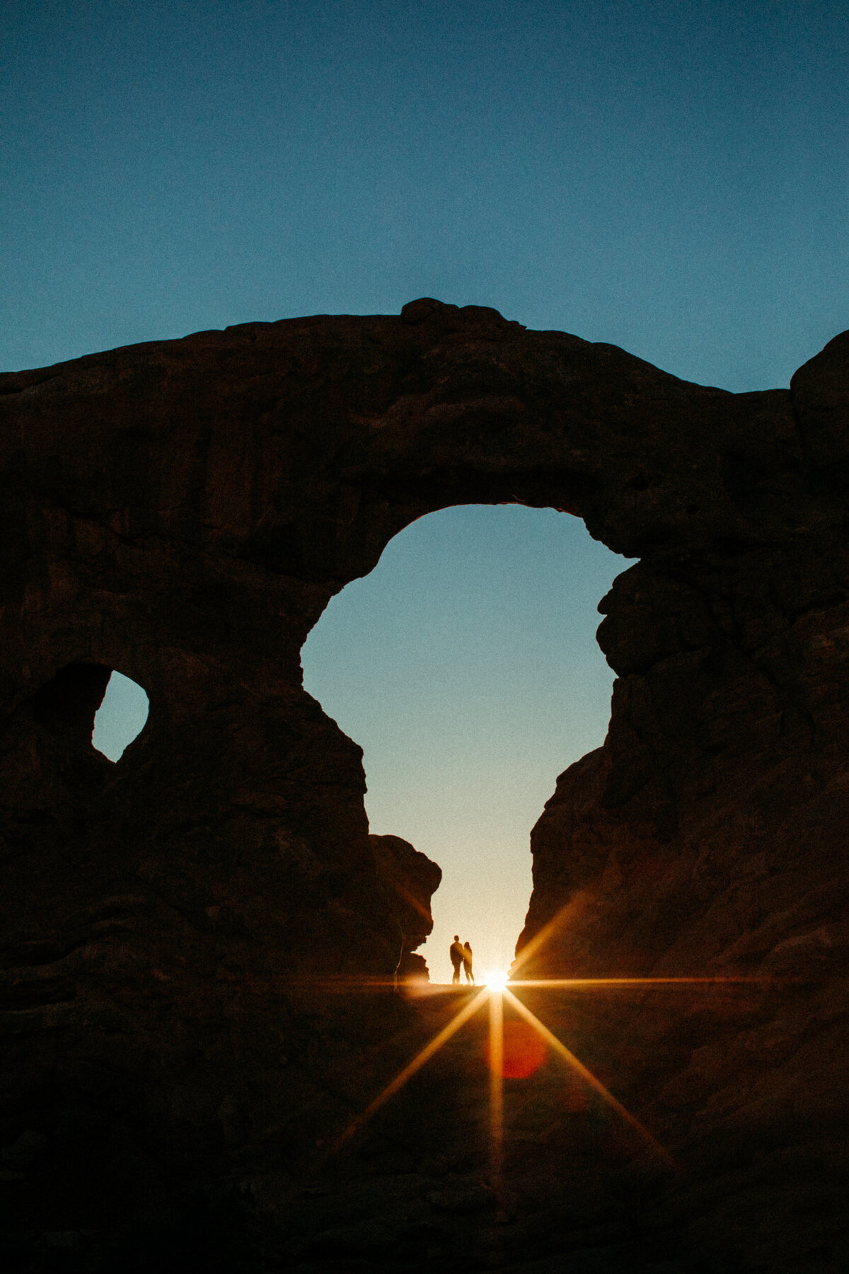 Silhouetted couple standing in an arch in the Moab desert