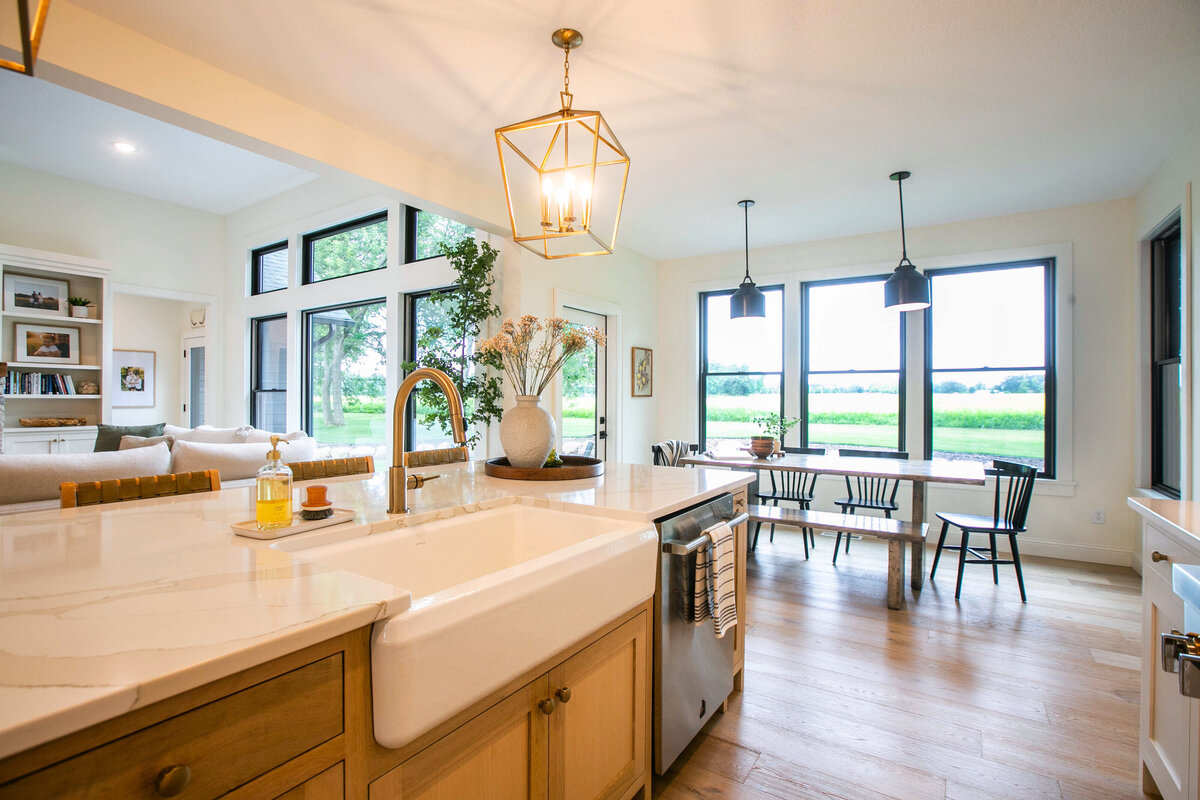Open kitchen with white cabinets, large island, and quartz countertops in an Otsego custom home