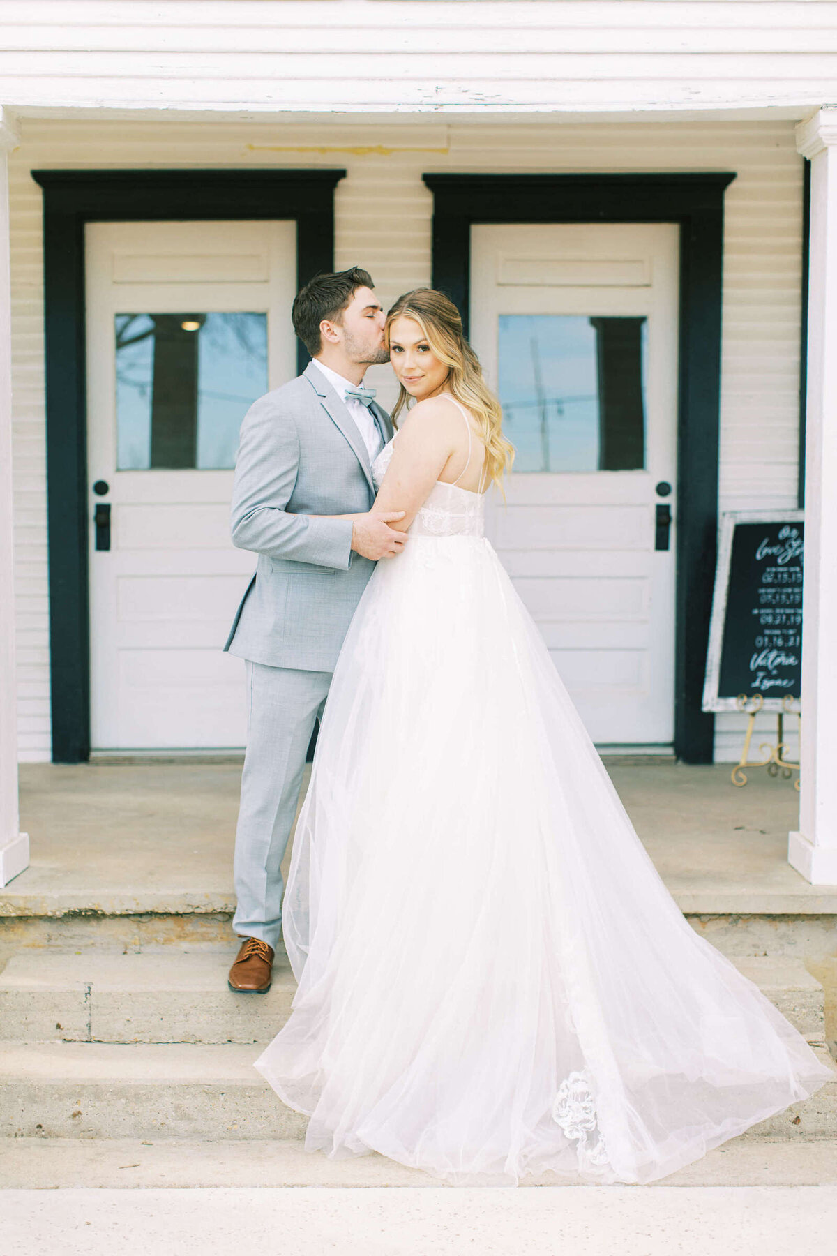 Groom kisses bride on the forehead at rustic wedding venue in Denton, Texas
