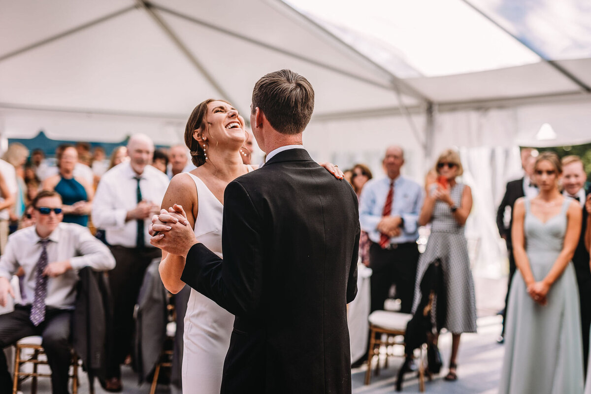 Bride laughing in beautiful sleek wedding dress during first dance with groom at Wentworth Inn wedding in Jackson NH by Lisa Smith Photography