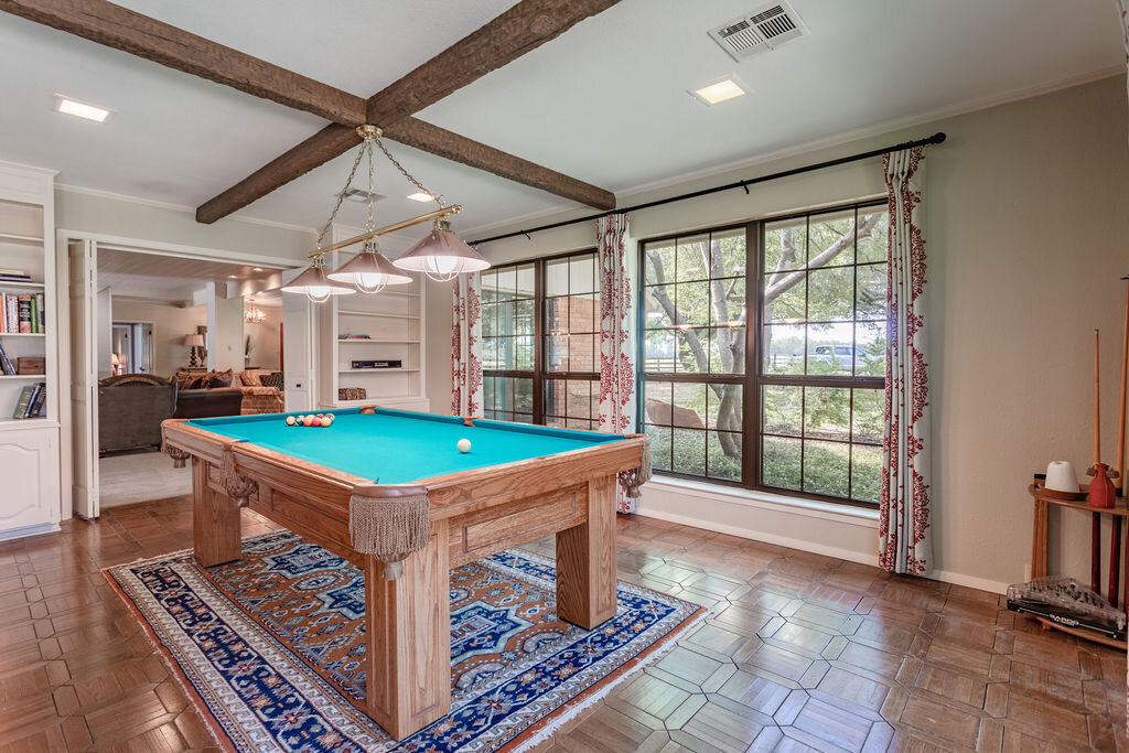 Living room with pool table and beautiful windows in this 5-bedroom, 4-bathroom vacation rental house for 16+ guests with pool, free wifi, guesthouse and game room just 20 minutes away from downtown Waco, TX.