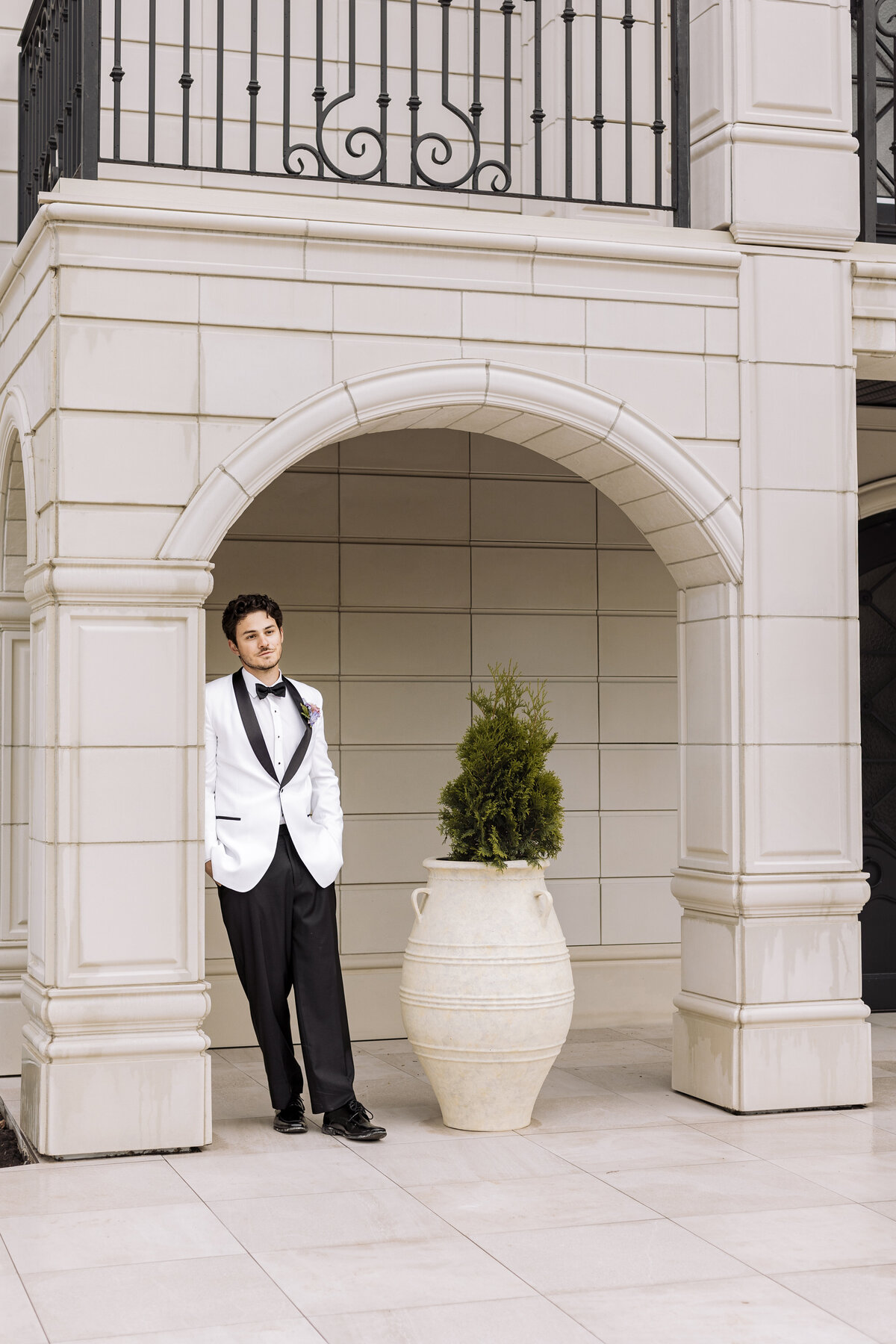 Groom leaning against Archway Manor main building