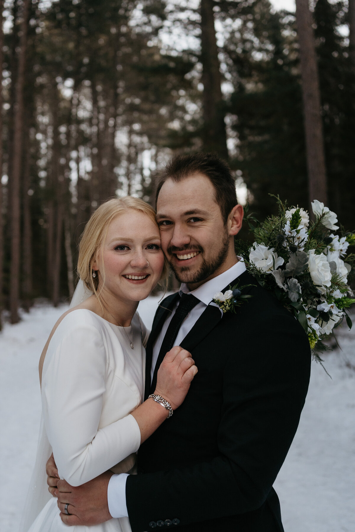 bride and groom embracing by forest