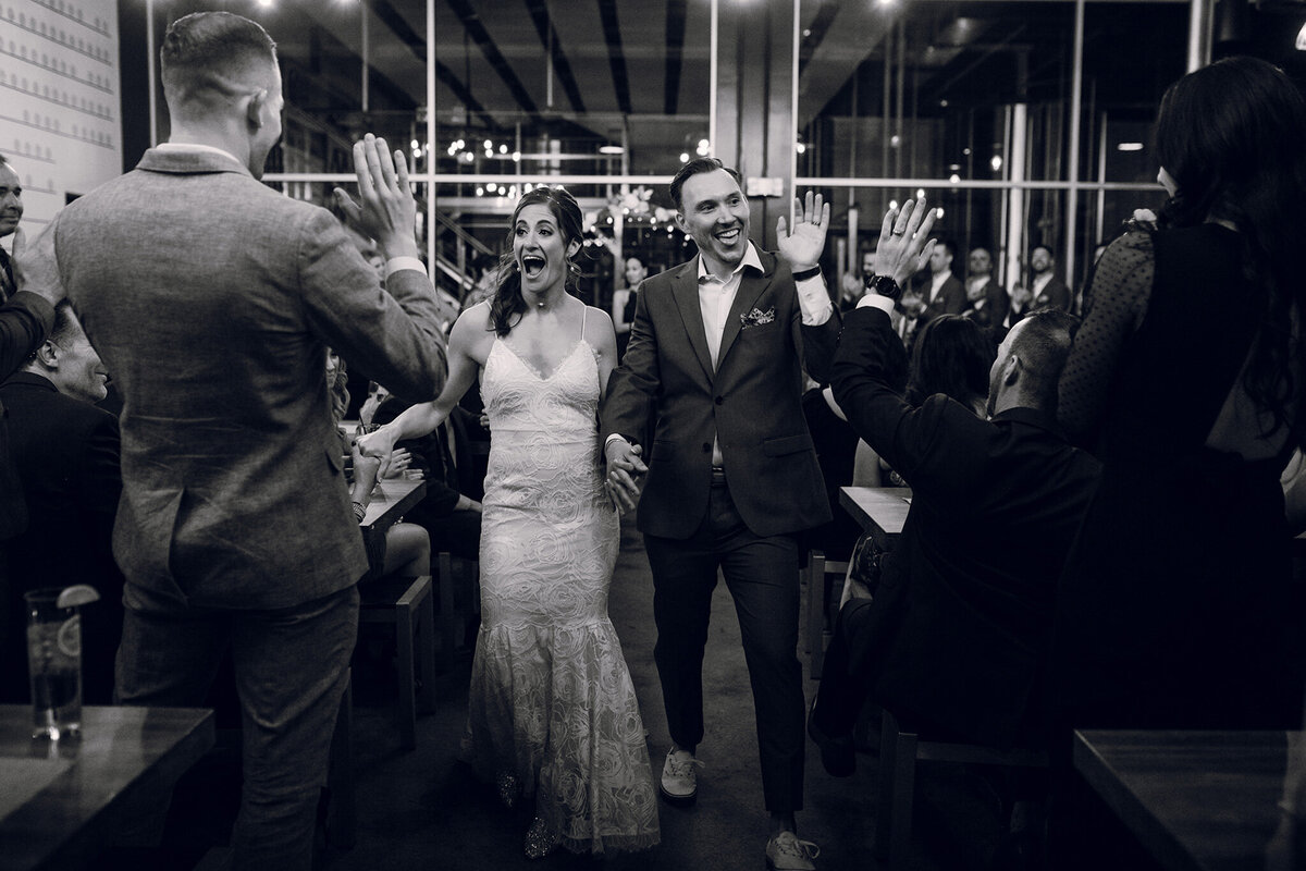 A bride and groom waving at each other in a restaurant.