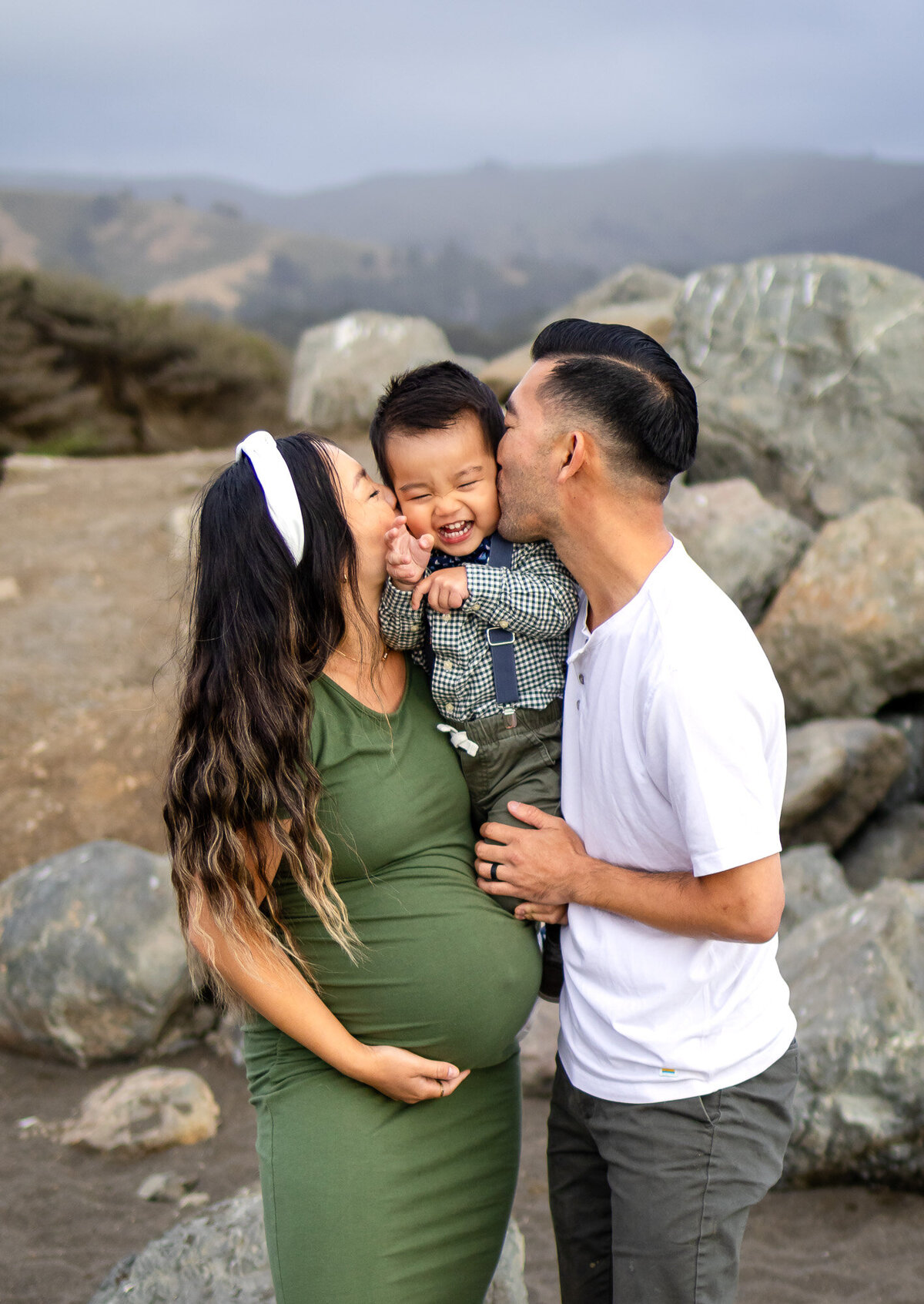 Close-up of joyful toddler being kissed on both cheeks by parents during maternity shoot, Bay Area Maternity Portfolio - Ellobelle Photography