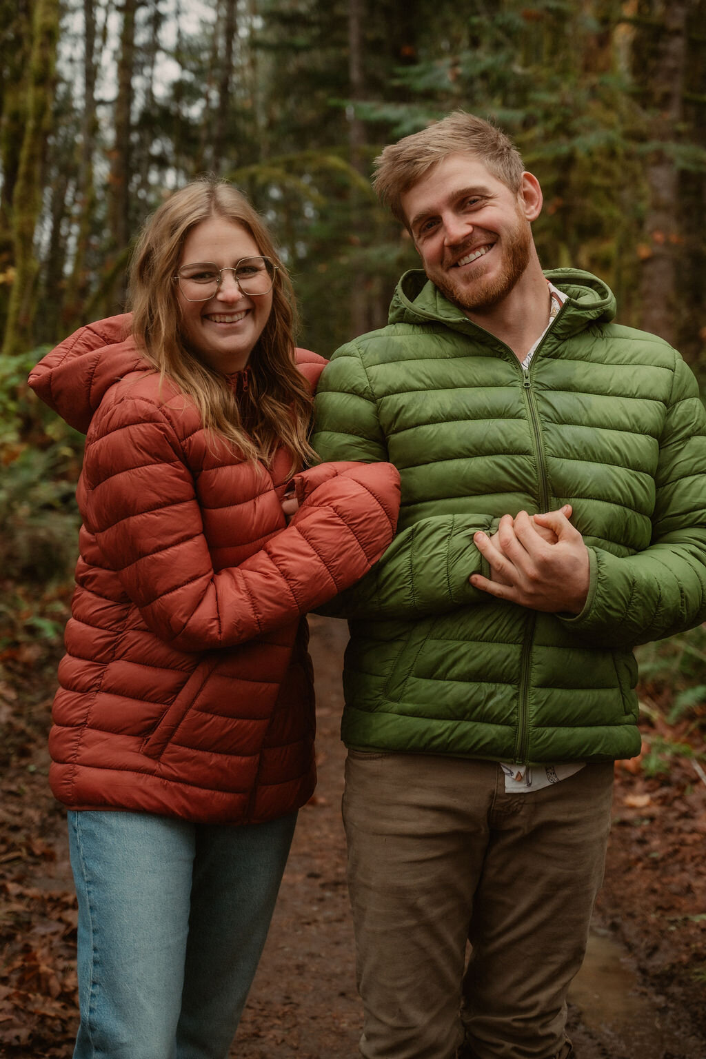 couple smiling in matching jackets in the forest