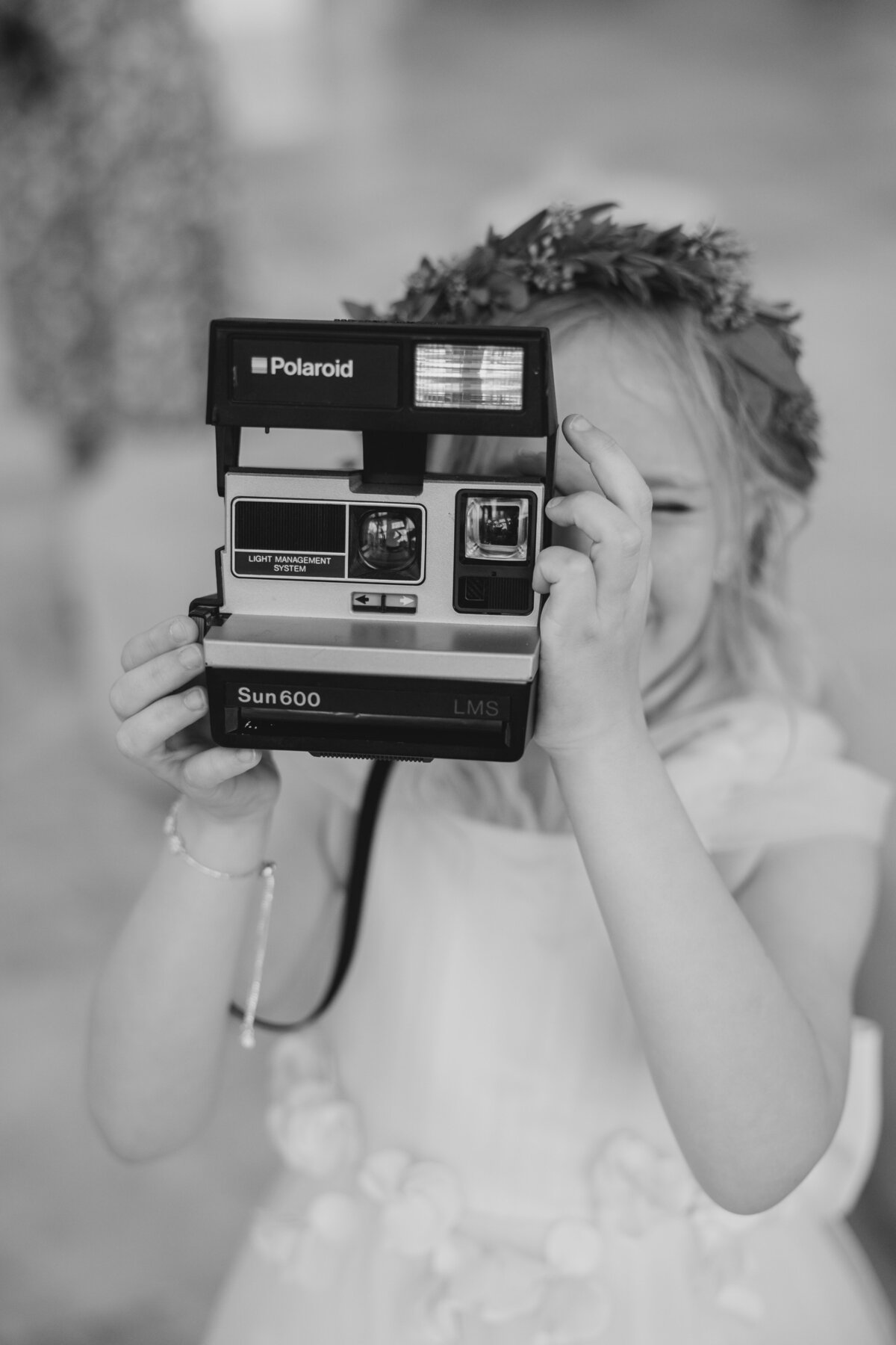 A young girl takes a photo with a Polaroid camera at a destination wedding