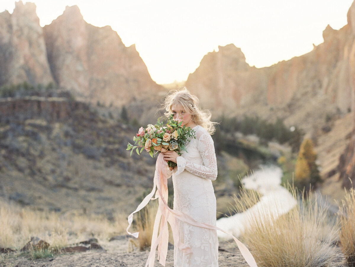 Outdoor wedding photographer captures a bride in a canyon holding her bouquet.