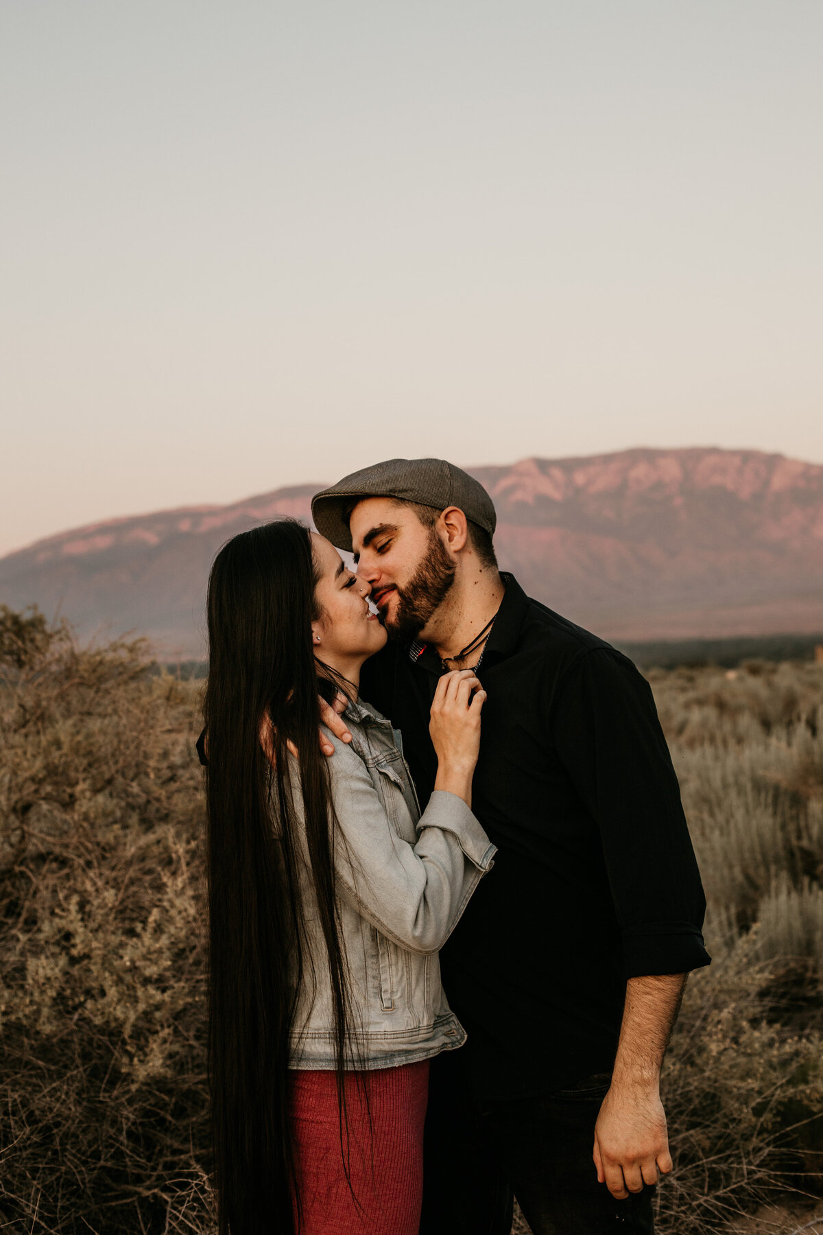 engaged couple about to kiss in front of mountain