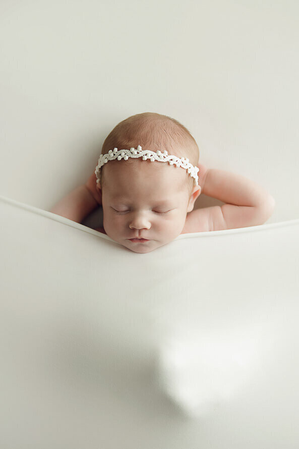 Baby sleeps with a white sheet covering her.