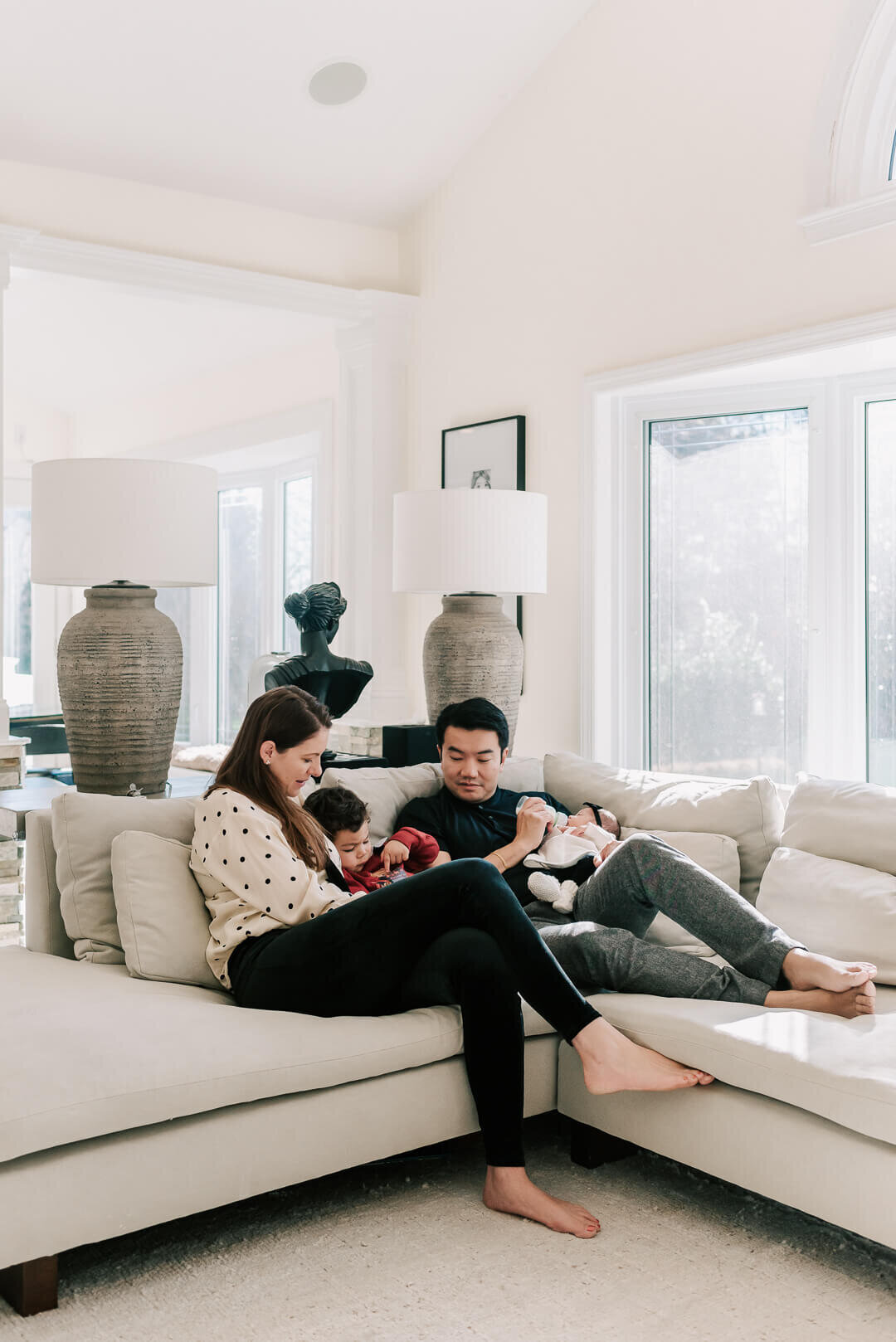 A family cuddling on a white sofa, enjoying their session with Denise Van Photography