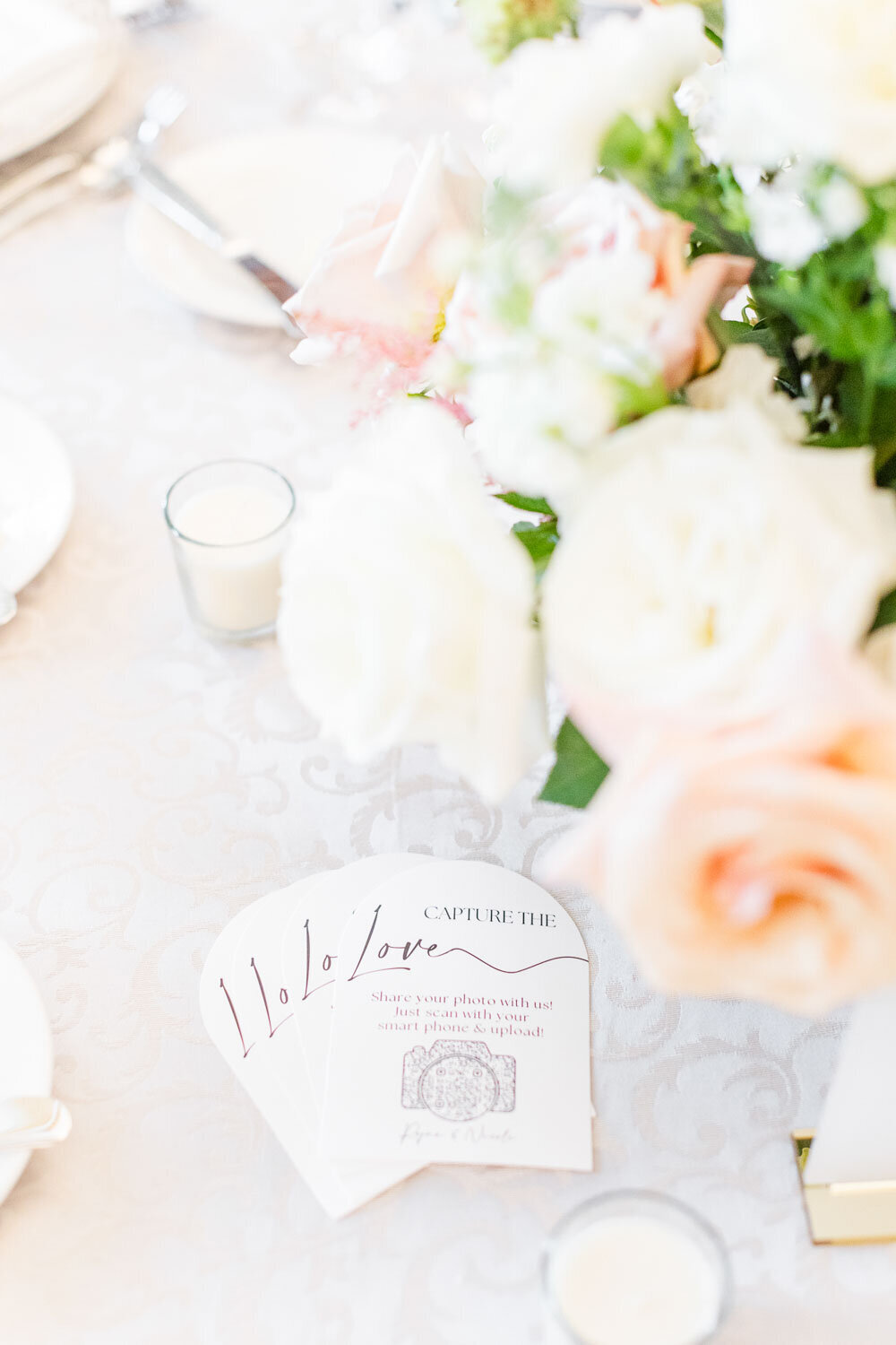 Reception table card with flowers and glassware.