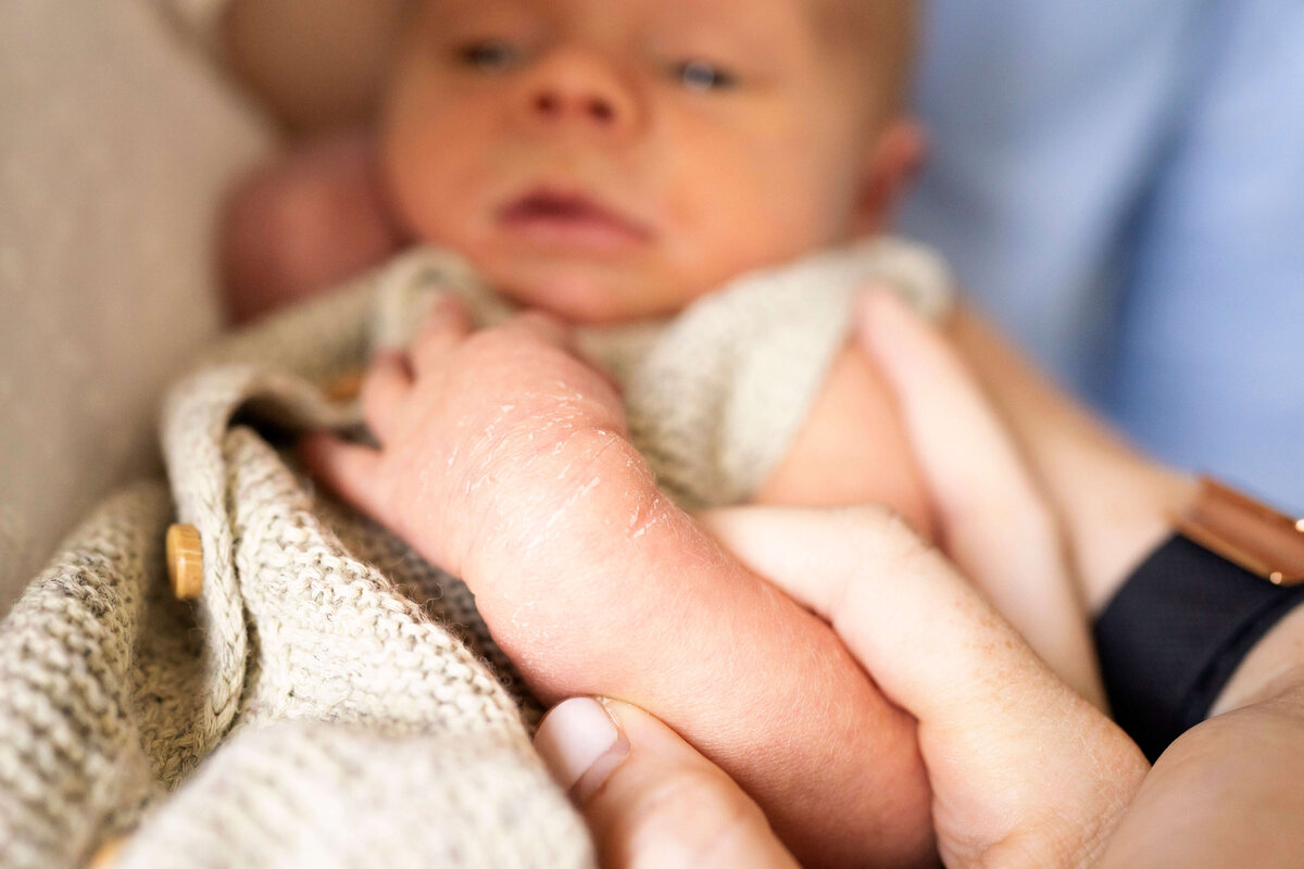 Close-up of newborn baby arm and hand in. mother's hand