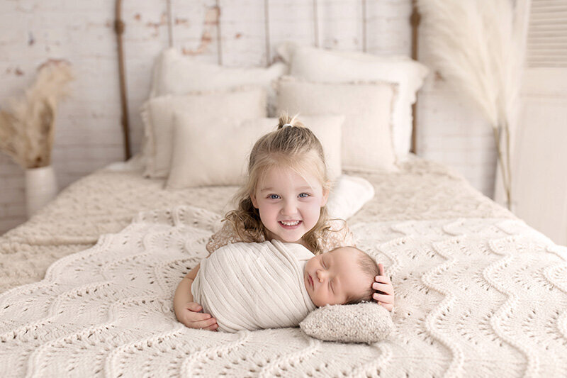 A big sister proudly shows off her baby brother