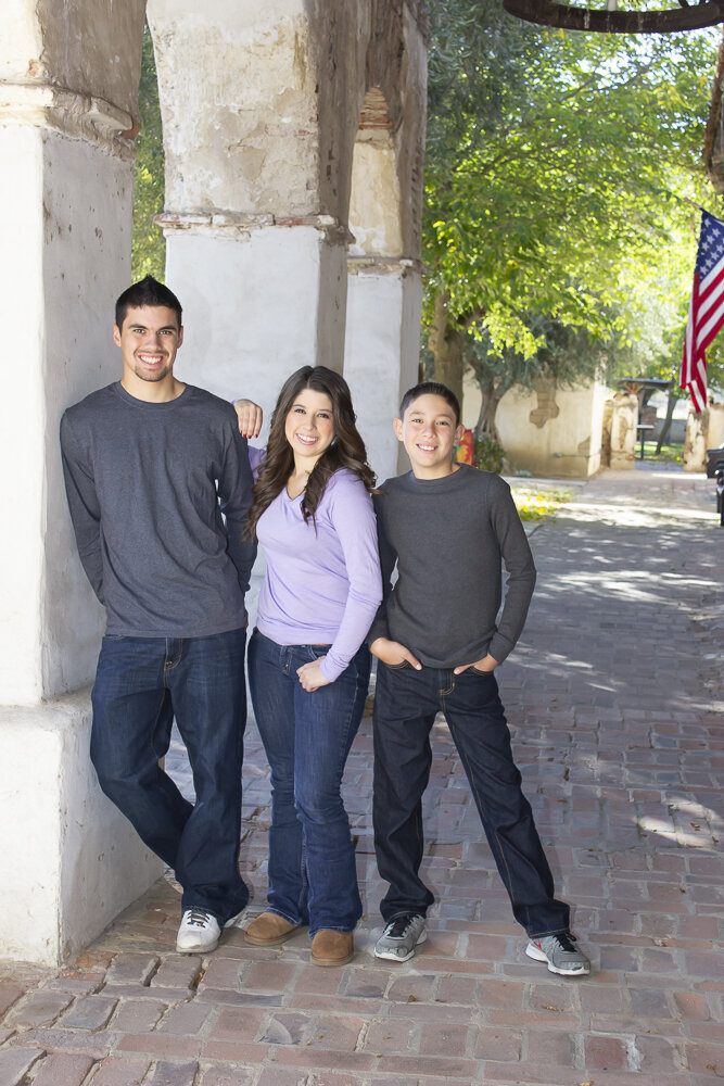 3 siblings posing at a Mission smiling with American Flag in background