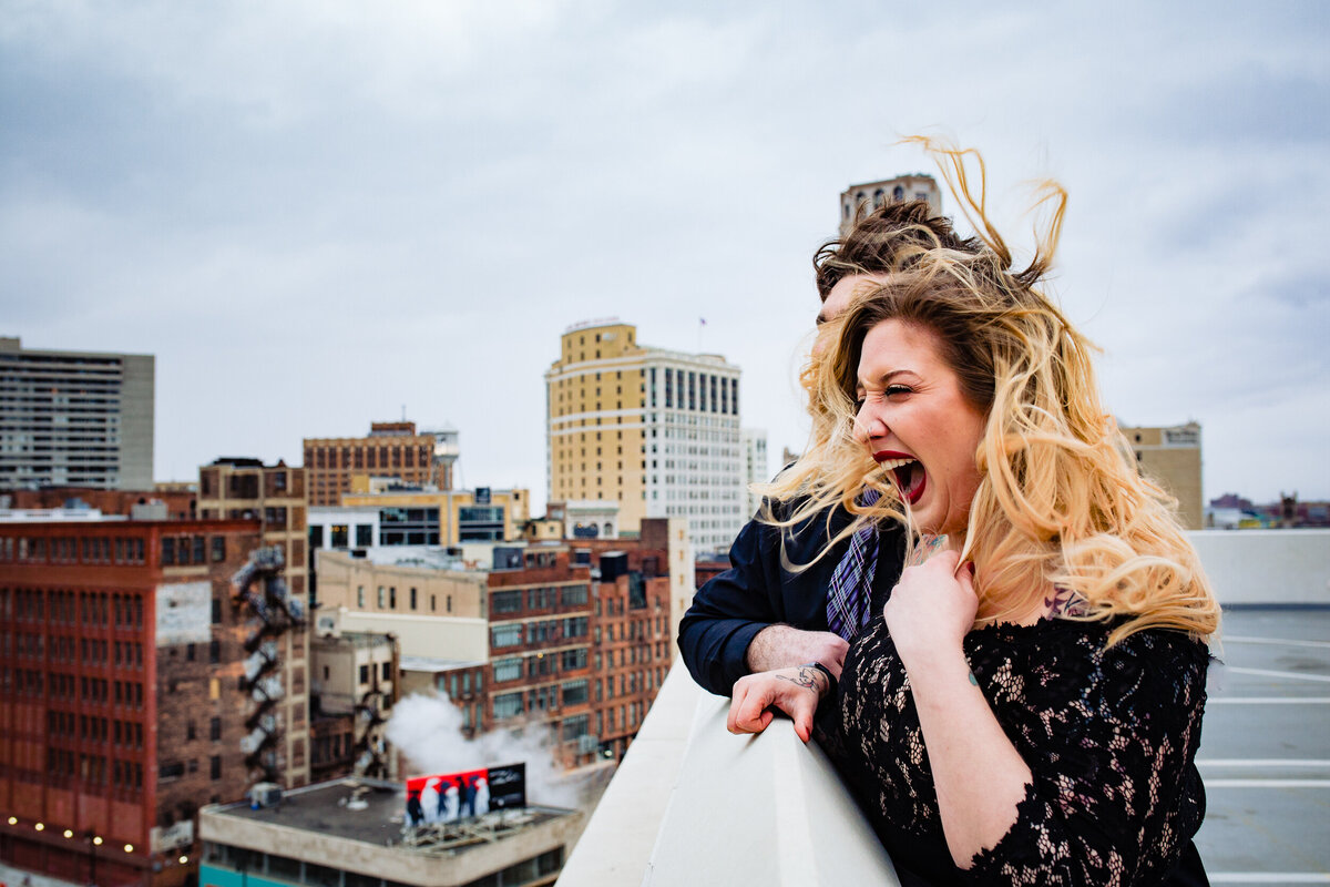 Engagement photos on the Z Park Garage in Detroit Michigan. THe wind blows the brides hair as she screams.  Photo By Adore Wedding Photography. Toledo Wedding Photographers