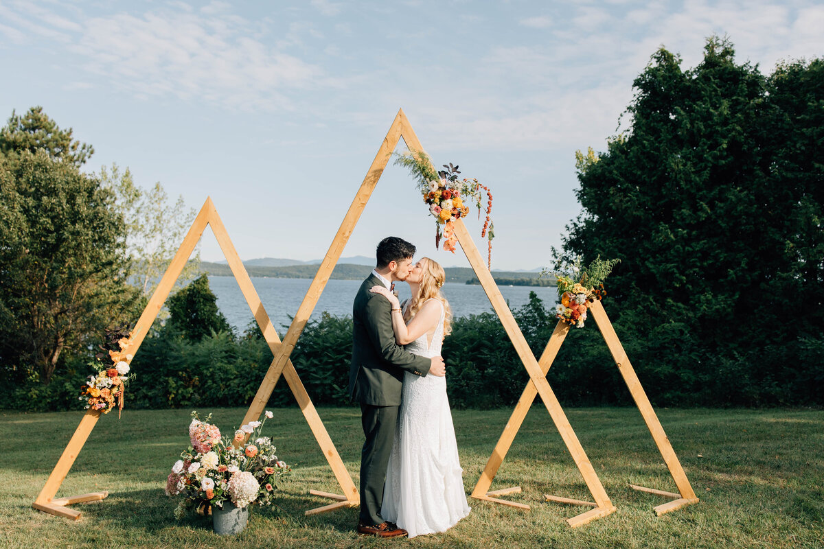 A newlywed couple shares a kiss at sunset on the shores of Lake Champlain in North Hero, Vermont during their intimate elopement