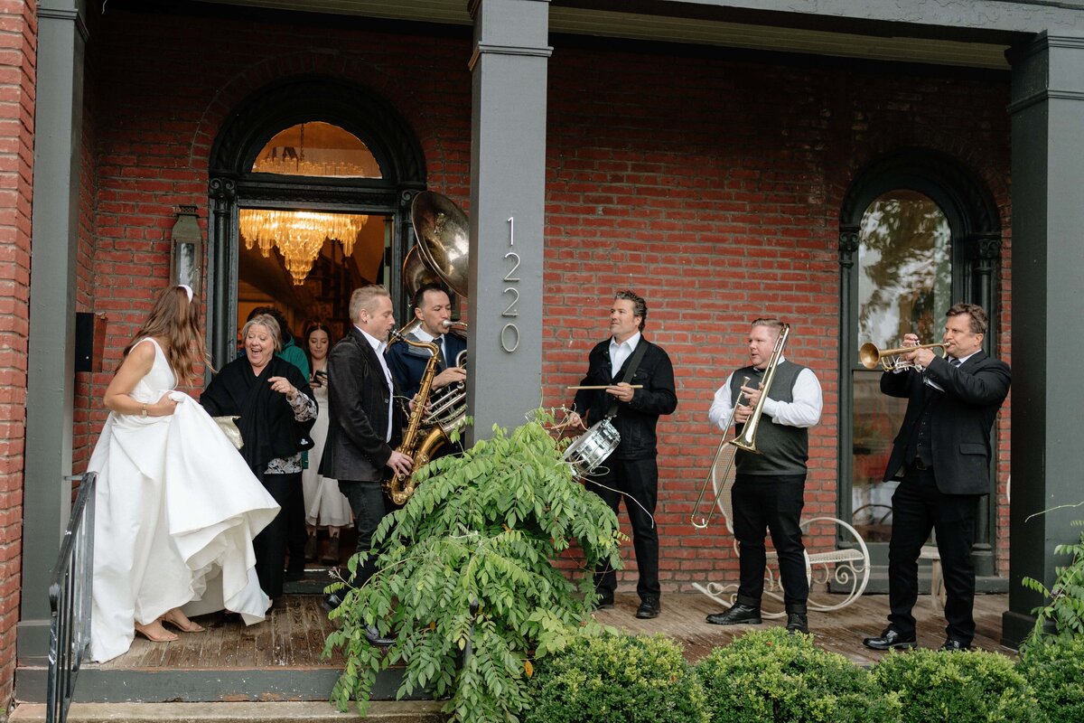 candid photo of bride gathering her guests and the brass band to walk through the streets of germantown in nashville