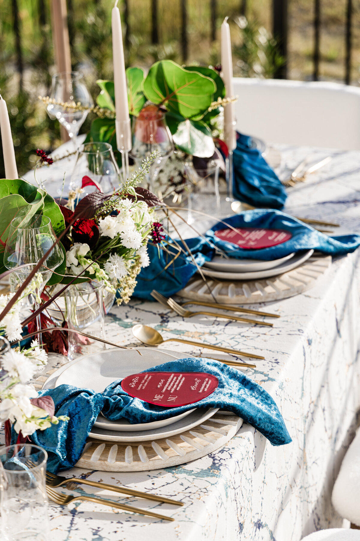 Ocean themed place settings with burgundy menu on crushed turquoise napkin on white ceramic plates on driftwood chargers