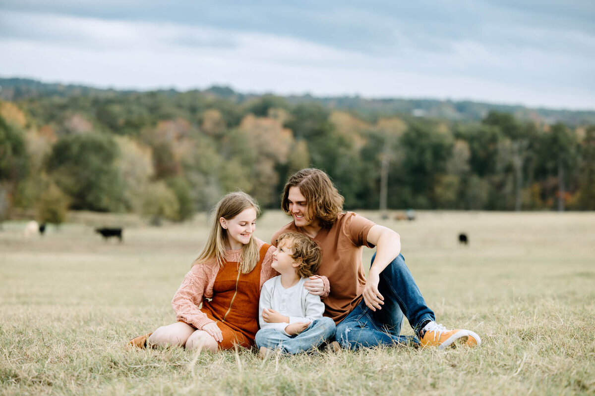photography of siblings sitting in pasture at El Cerrito Lodge during family portrait session