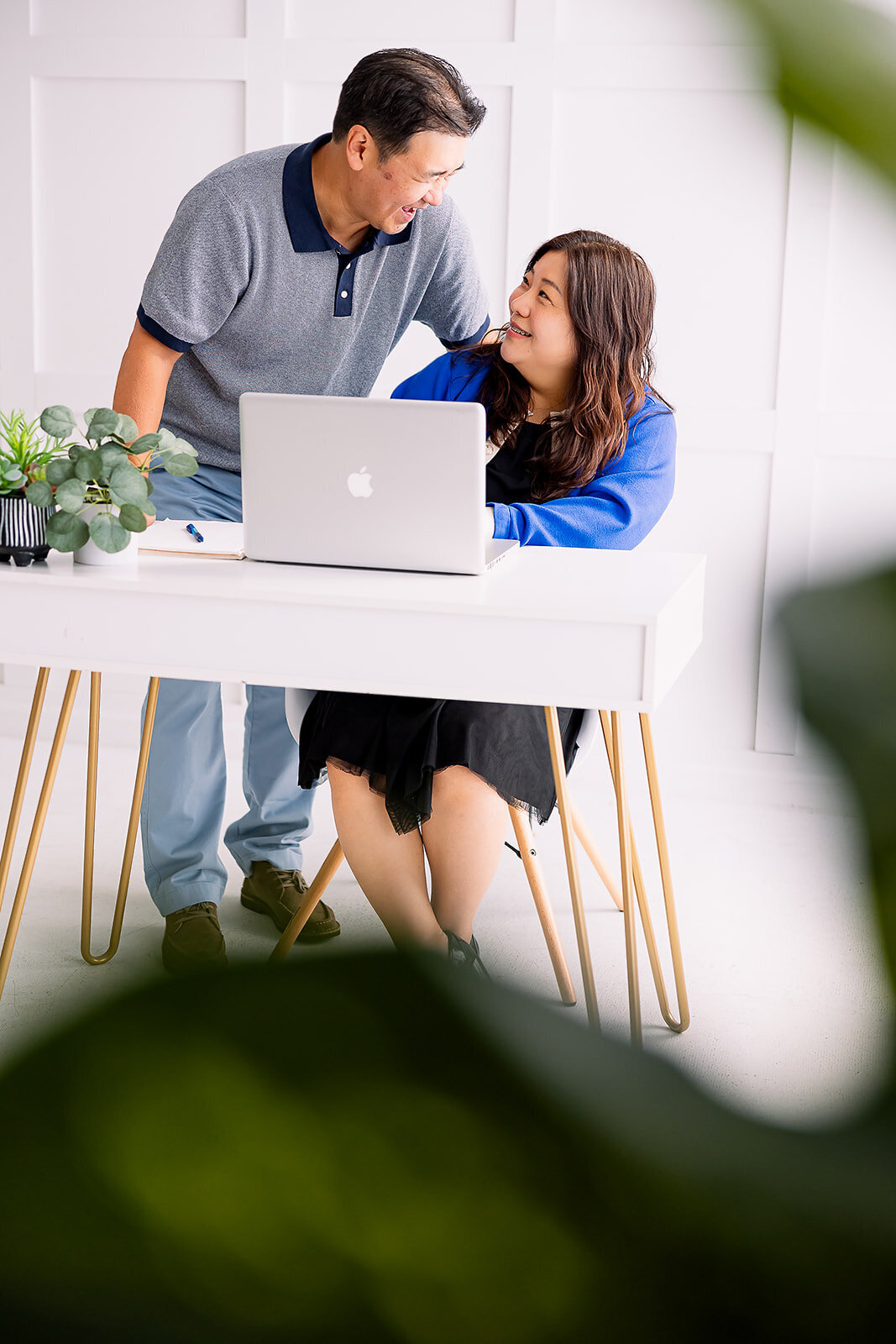 Man looking over woman's shoulder while she sits and types at a computer