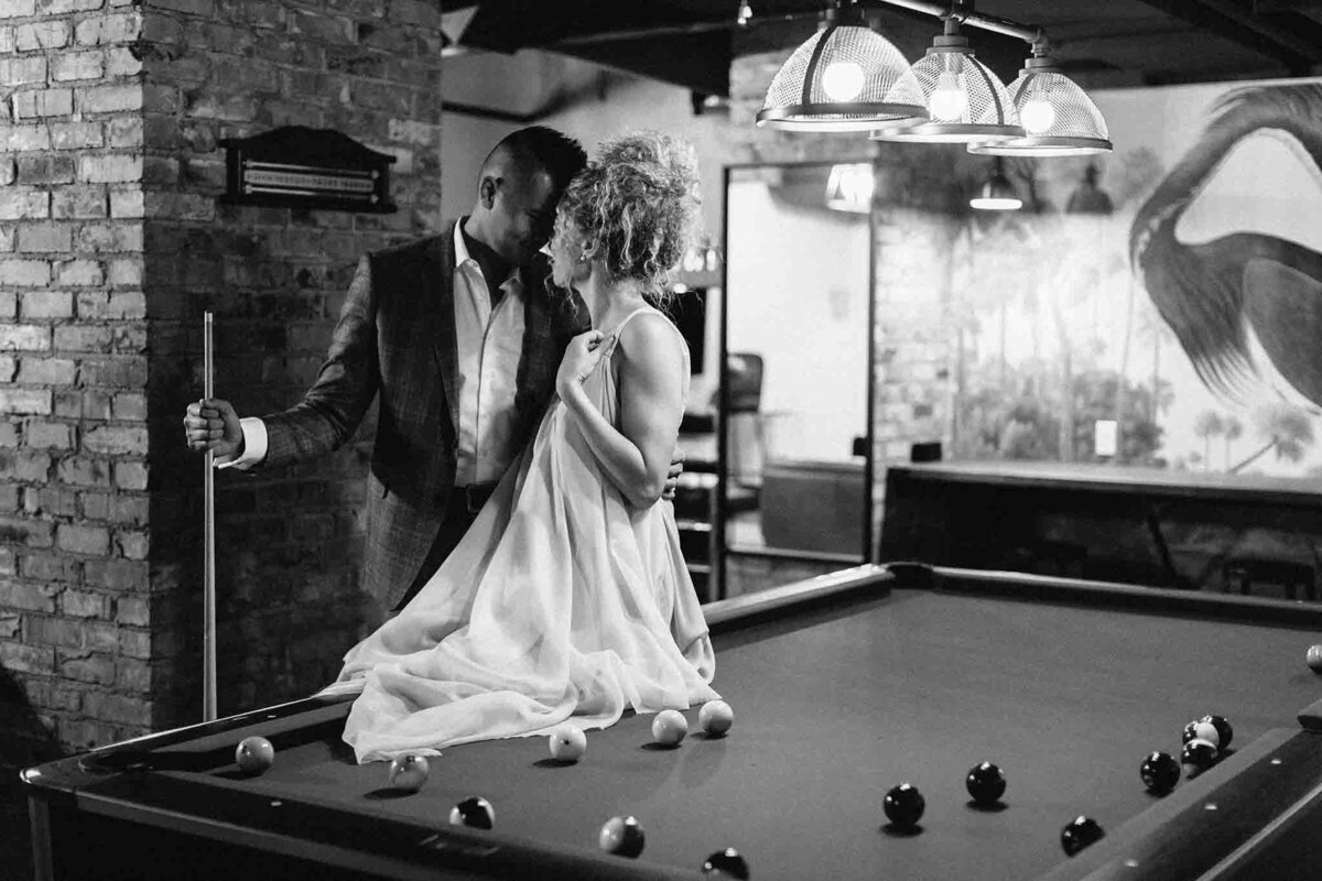 Bride and groom playing pool at Venue 308, a historical warehouse wedding venue in Calgary, featured on the Brontë Bride Vendor Guide.