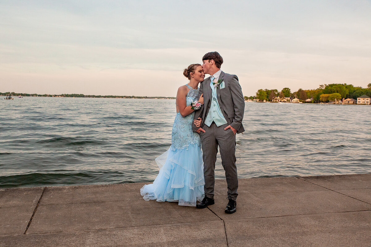Prom couple in front of water during sunset