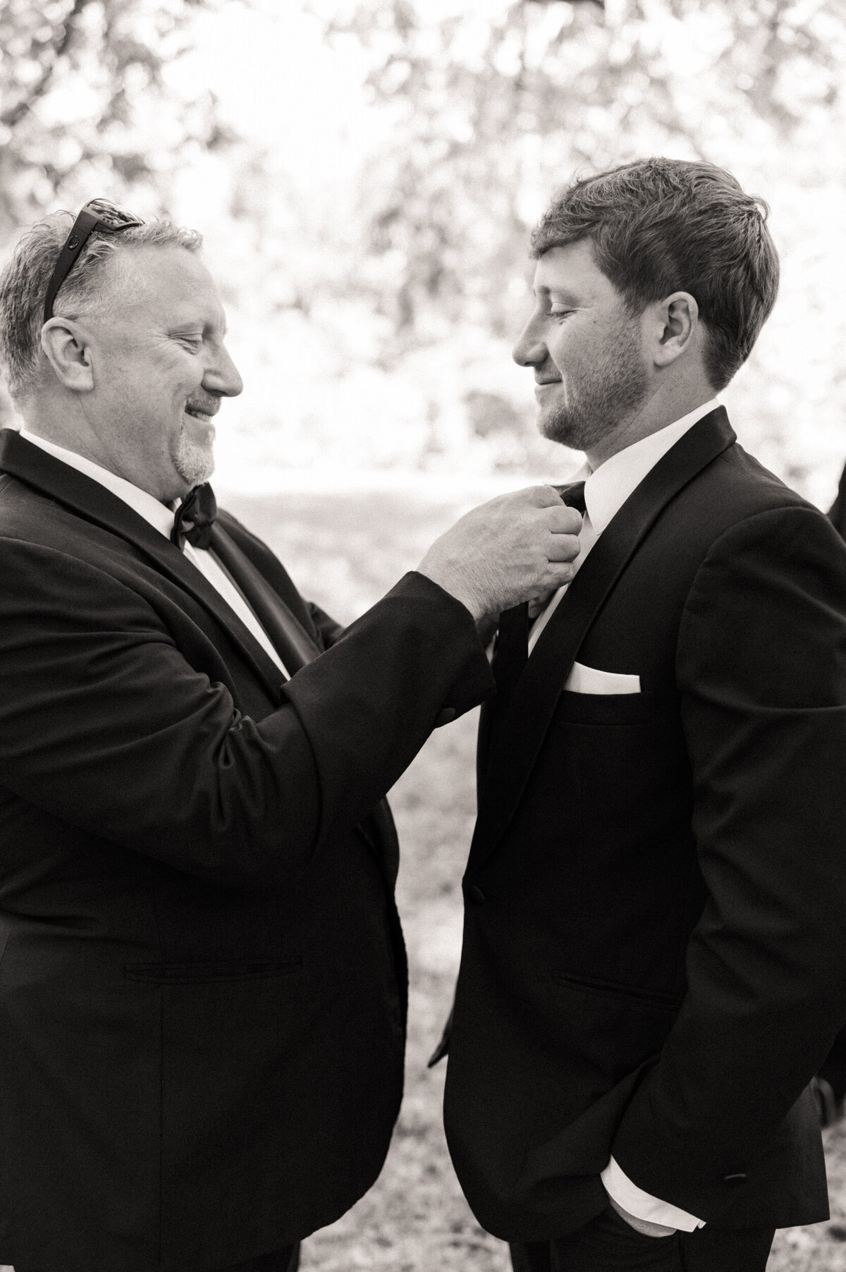 Groom's dad helping his son get ready and tying his tie on his wedding day