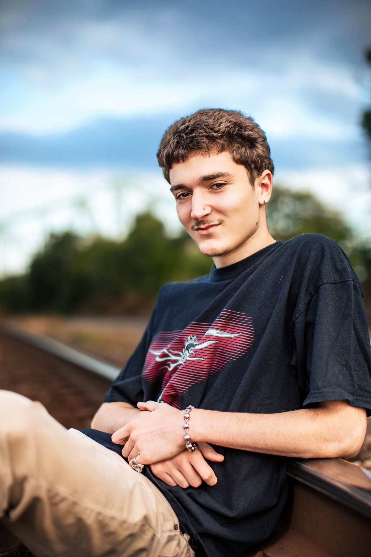 A senior boy sits with the Sewickley bridge in the backdrop for his senior photography session