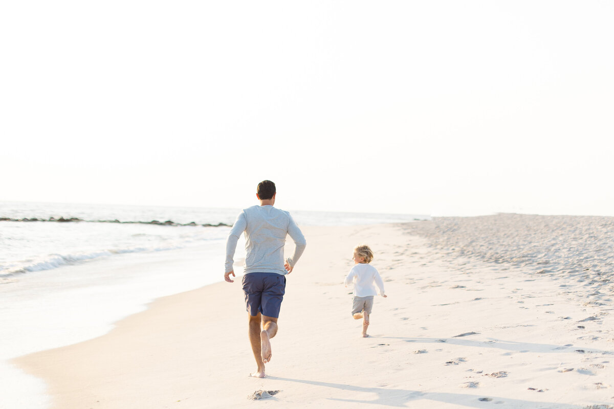 Dad chases his son down the beach during family portrait session