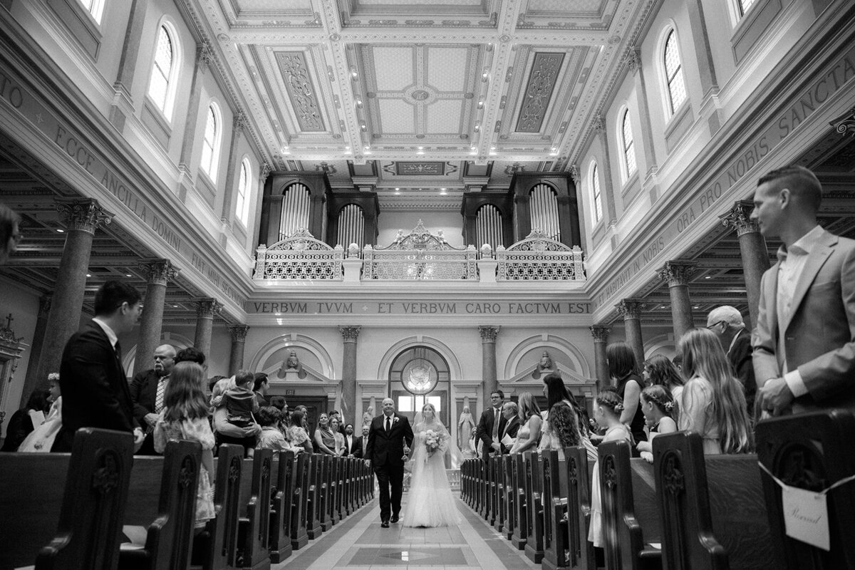 Black and white photo of a father walking his daughter down the aisle at the Cathedral of the Incarnate in Nashville, TN. 