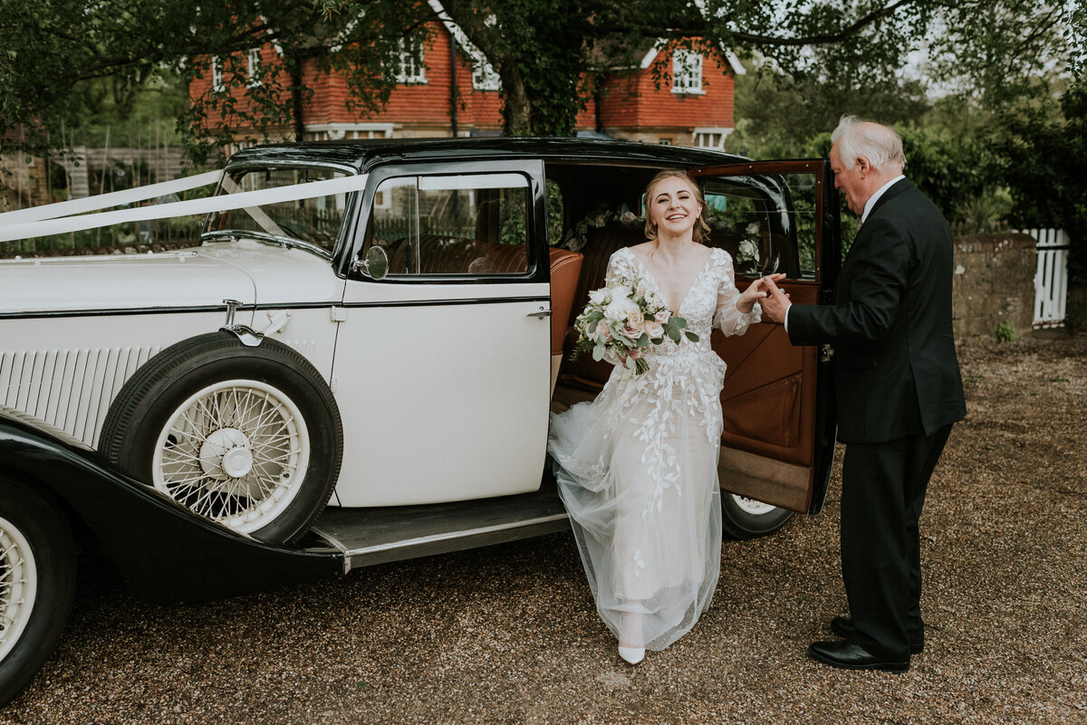 Bride getting out vintage car outside church