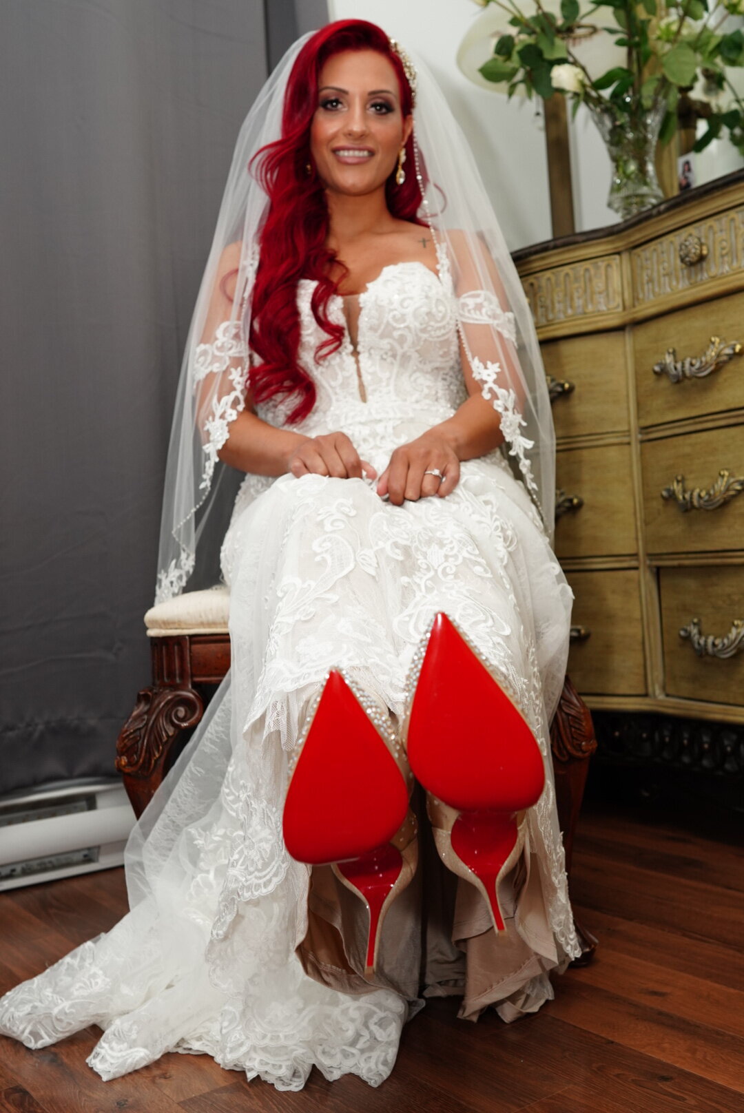 A bride proudly displays her elegant shoes, highlighting the intricate design and details of her bridal footwear. This image captures a playful and stylish moment, adding a personal touch to her bridal portrait while showcasing the complete look of her wedding attire.