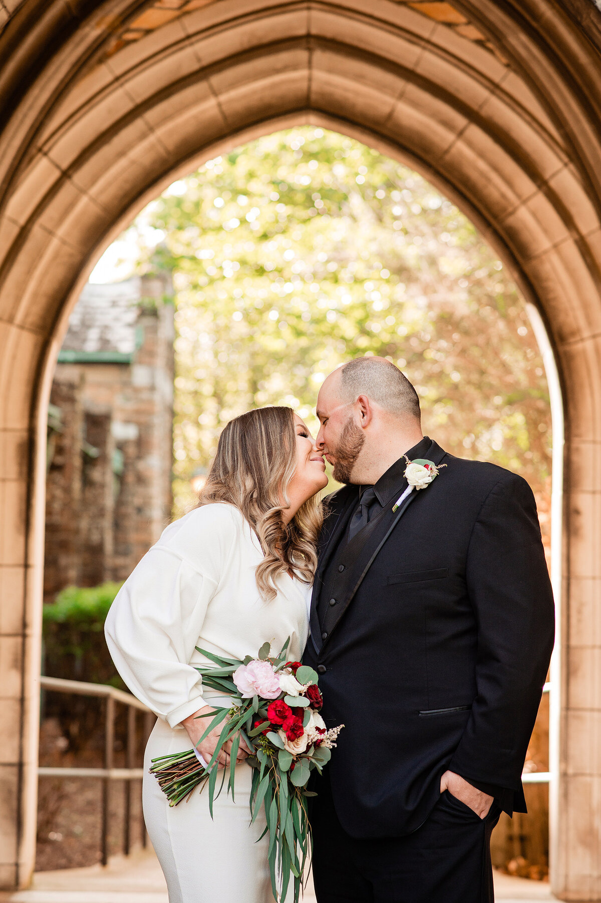 Couple snuggled together closely under an arch at Scarritt Bennett