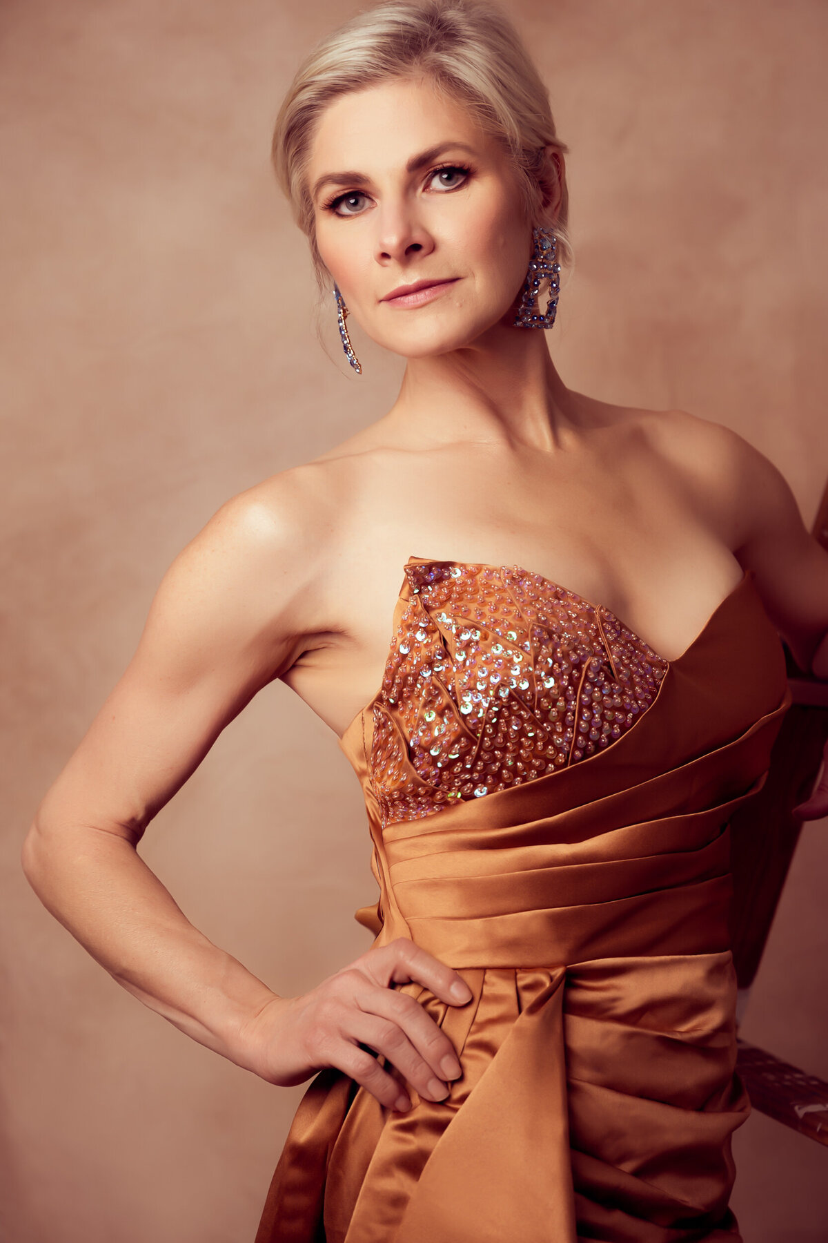 A close up of a blond woman wearing a orange gown