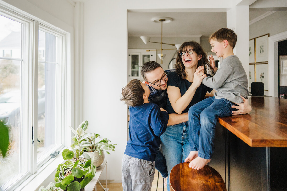 family laughs together in modern kitchen space