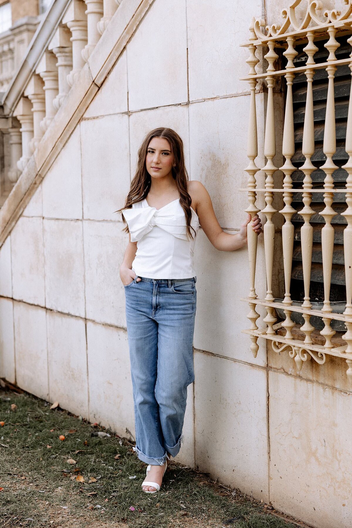 Senior session of a girl standing next to a window.